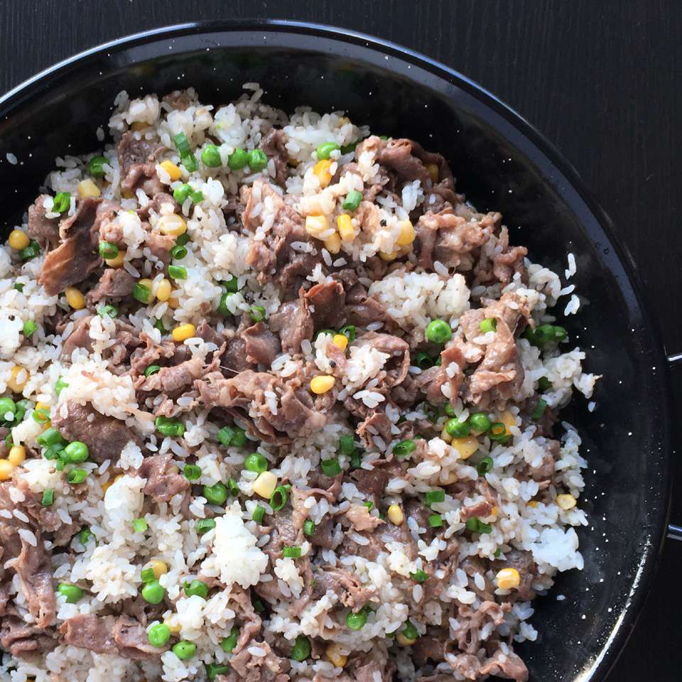 rice with beef, peas, and corn in wok