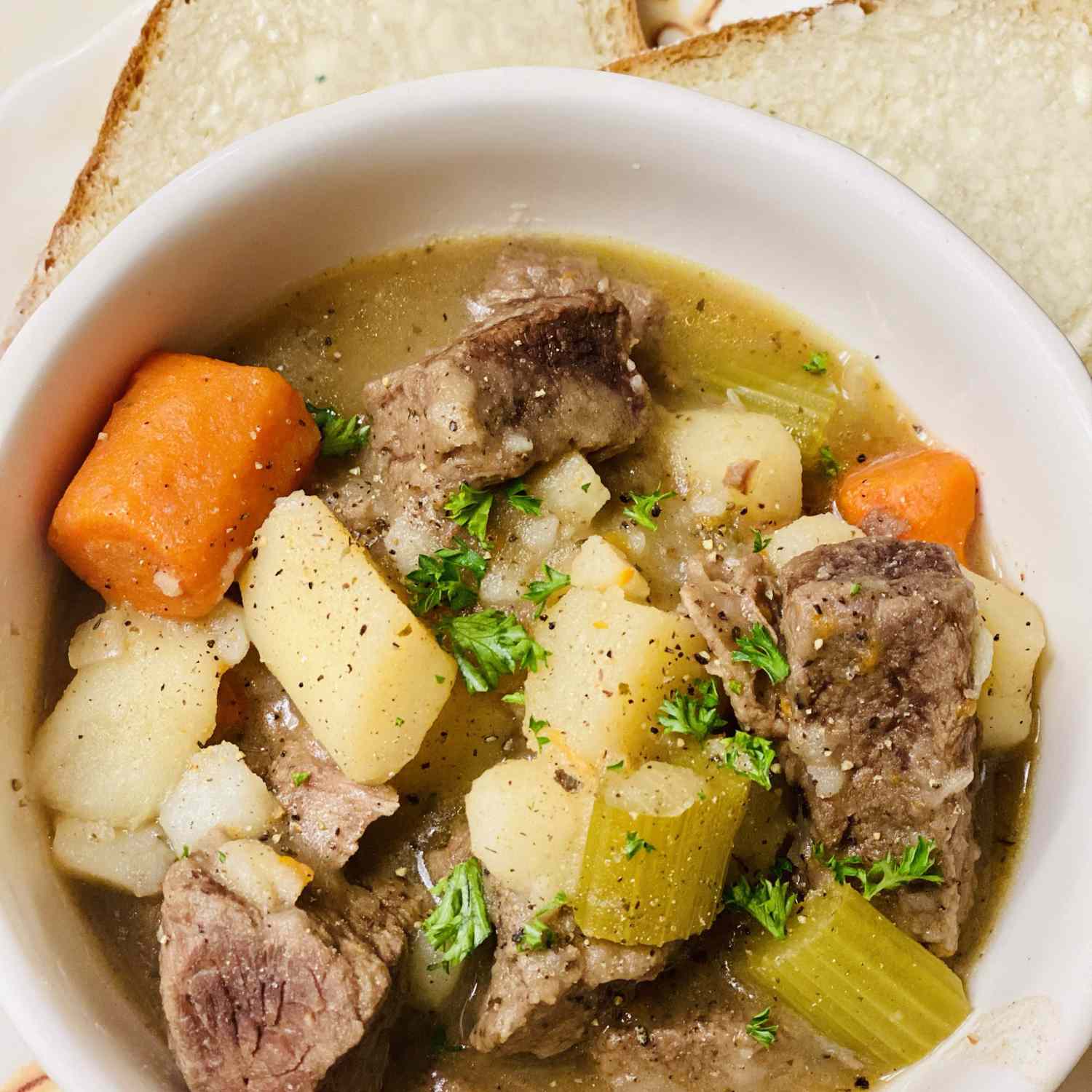 overhead view of a bowl of homemade Beef Stew VI with beef, potatoes, celery, and carrots
