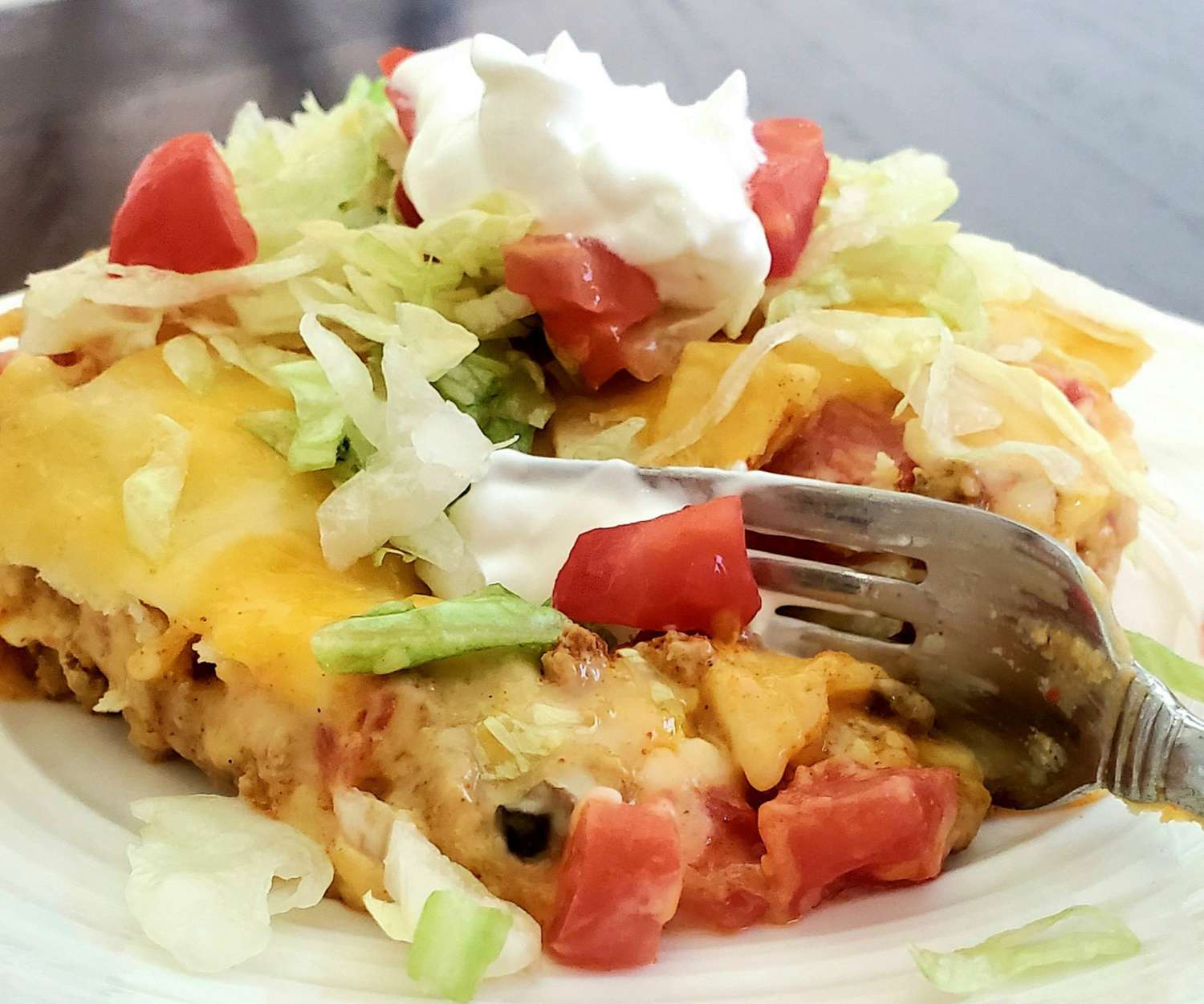 enchiladas with cheese, lettuce, tomato, and sour cream topping