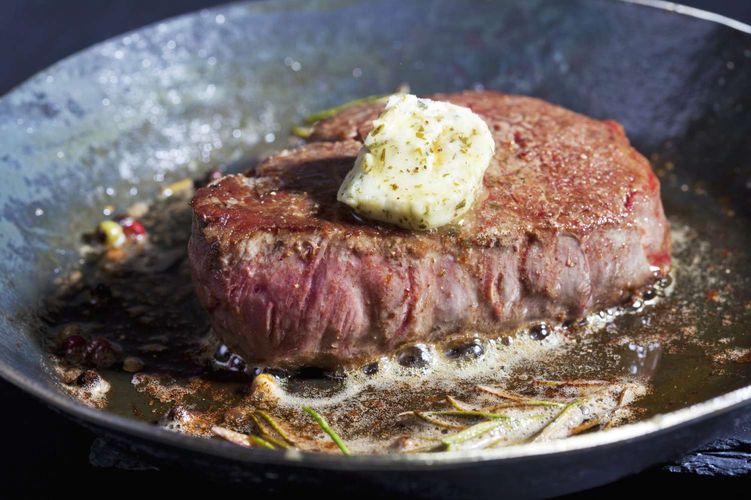 Fried filet of beef with herb butter, peppercorns and rosemary in a pan