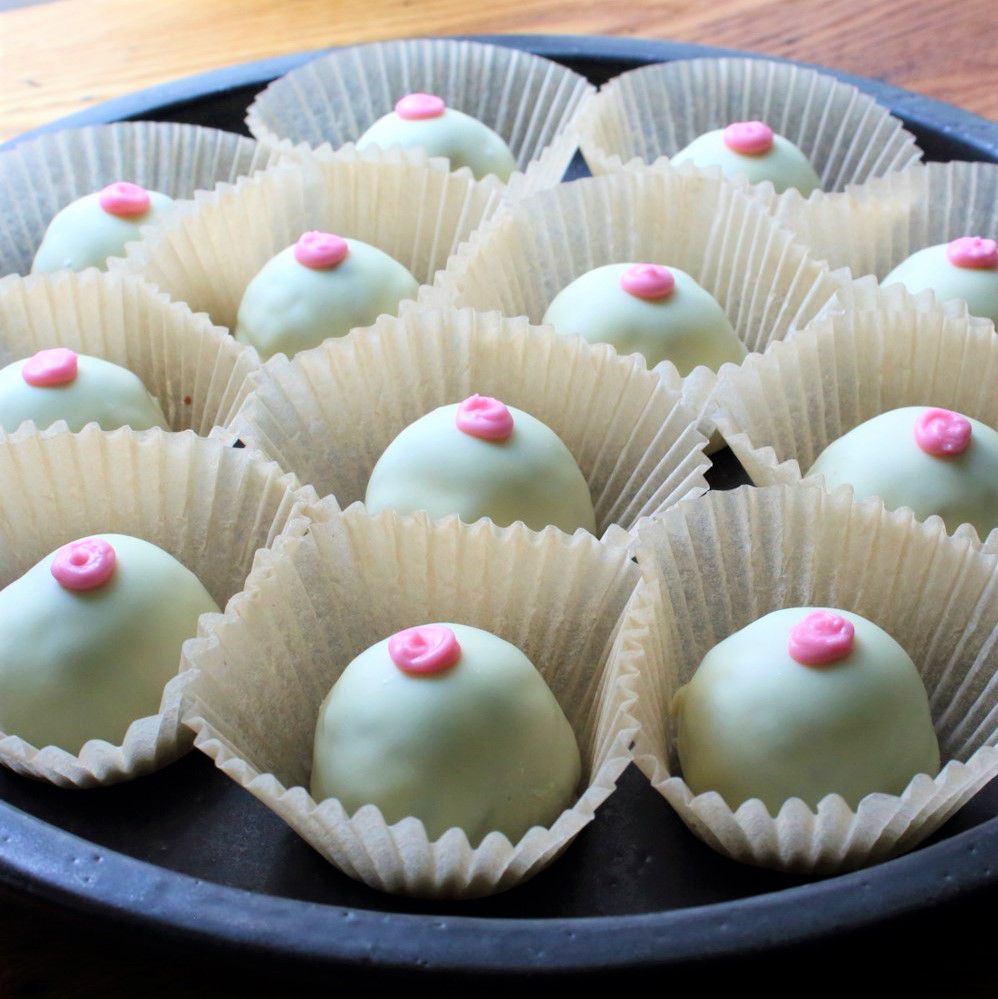a tray of the Italian confections called nipples of venus which look like small light green balls with a red dot of icing in the center