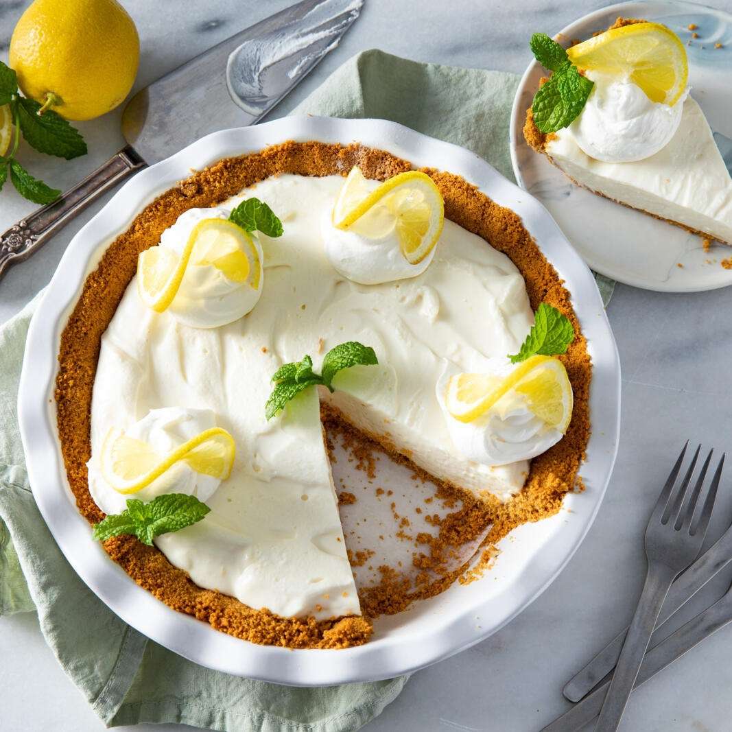 overhead view of homemade Lemon Ice Box Pie III garnished with whipped cream, lemon slices, and mint leaves