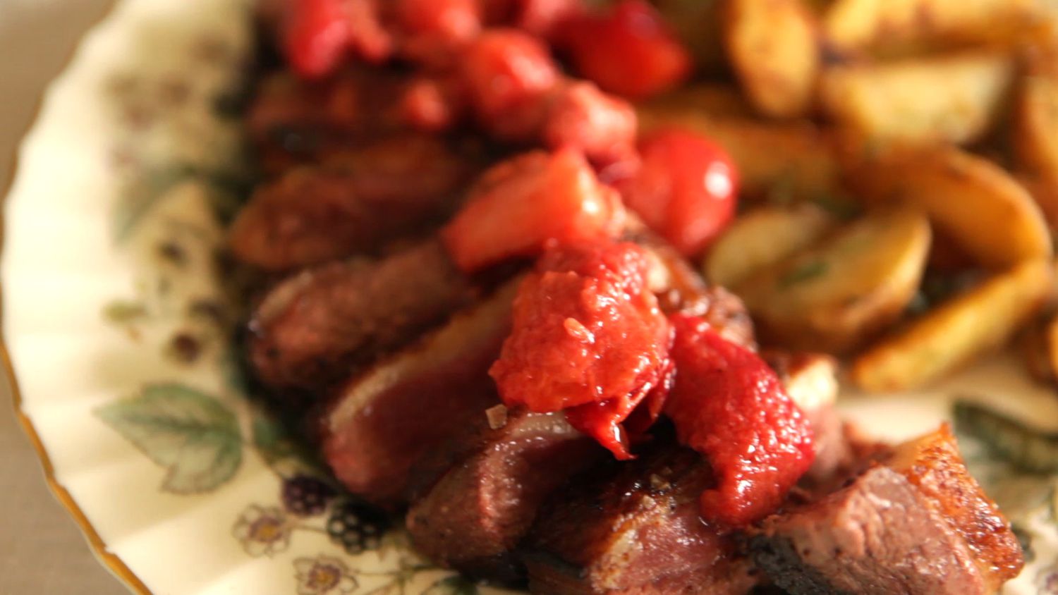 closeup of medium-rare sliced duck breast topped with a strawberry, raspberry, and red plum sauce