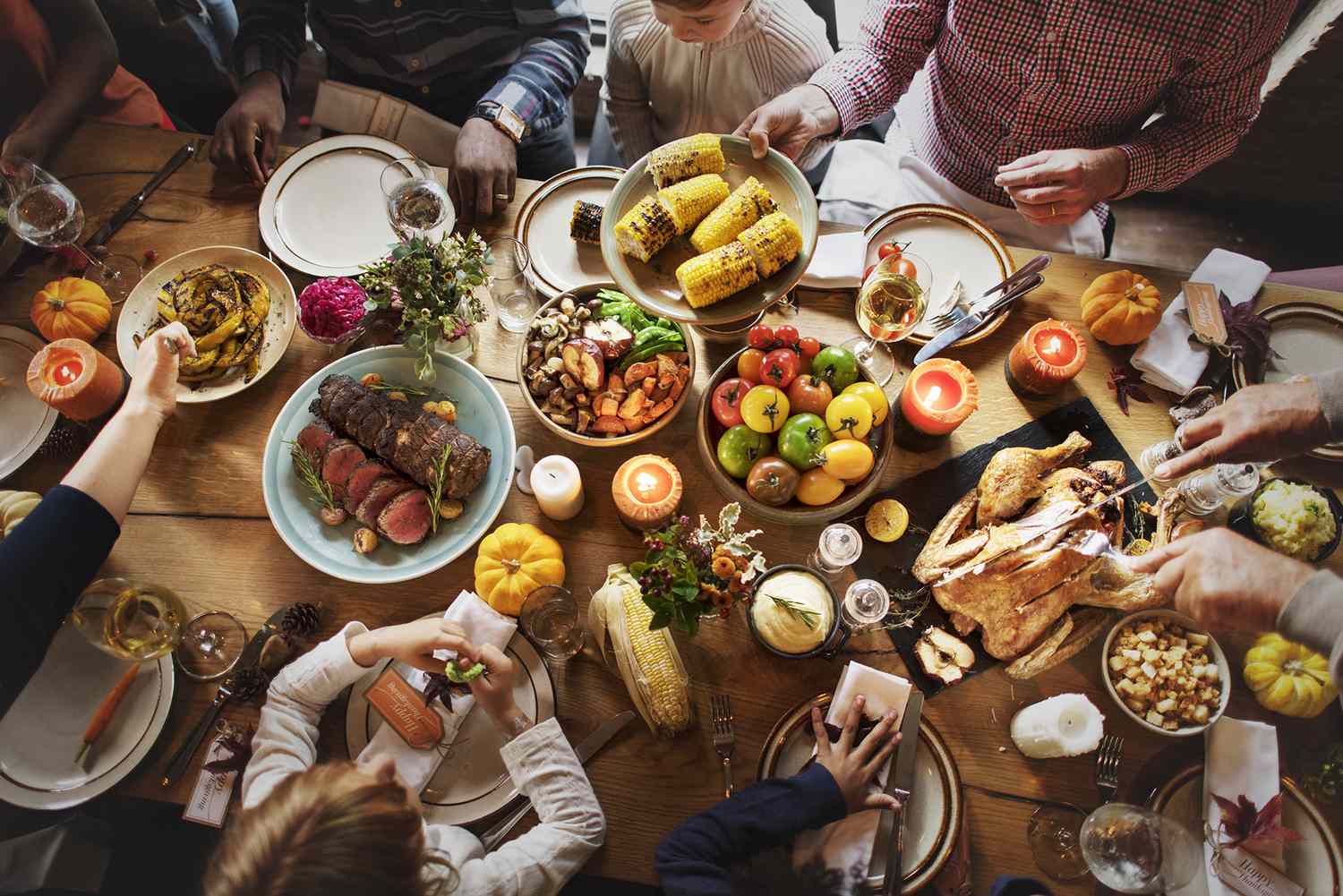 overhead view of friends gathered around a table set with a Thanksgiving dinner