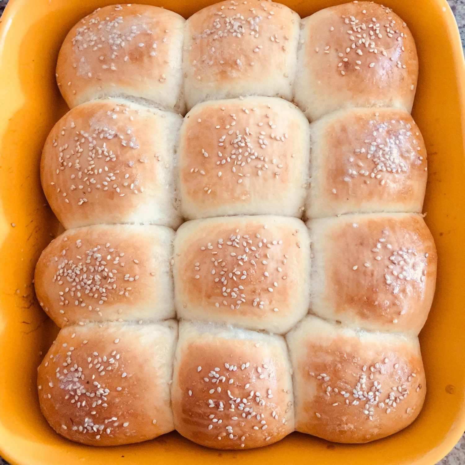 overhead view looking down into homemade Soft Dinner Rolls recipe topped with sesame seeds and baked in a 9x13 dish