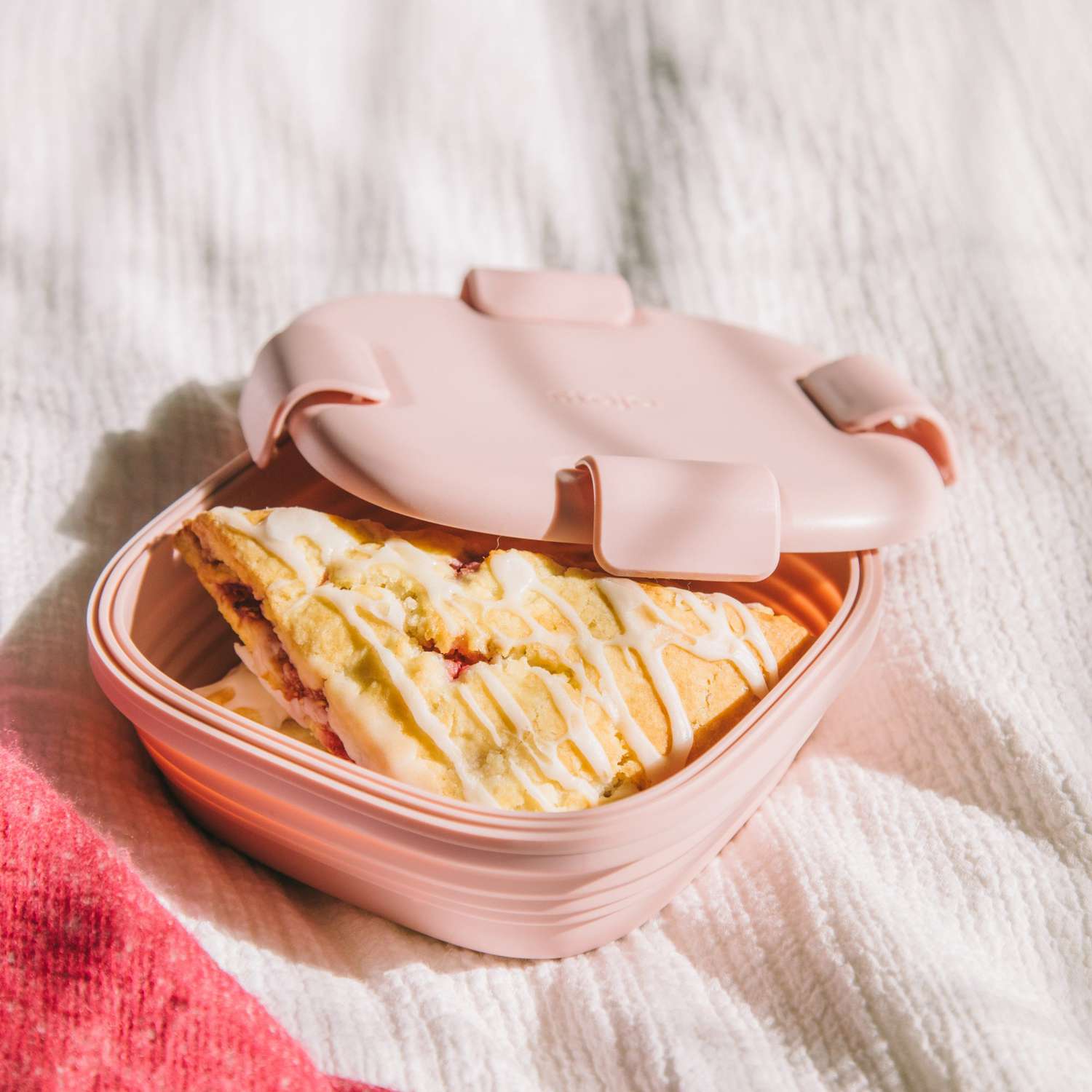 pink collapsible food storage container with scone inside