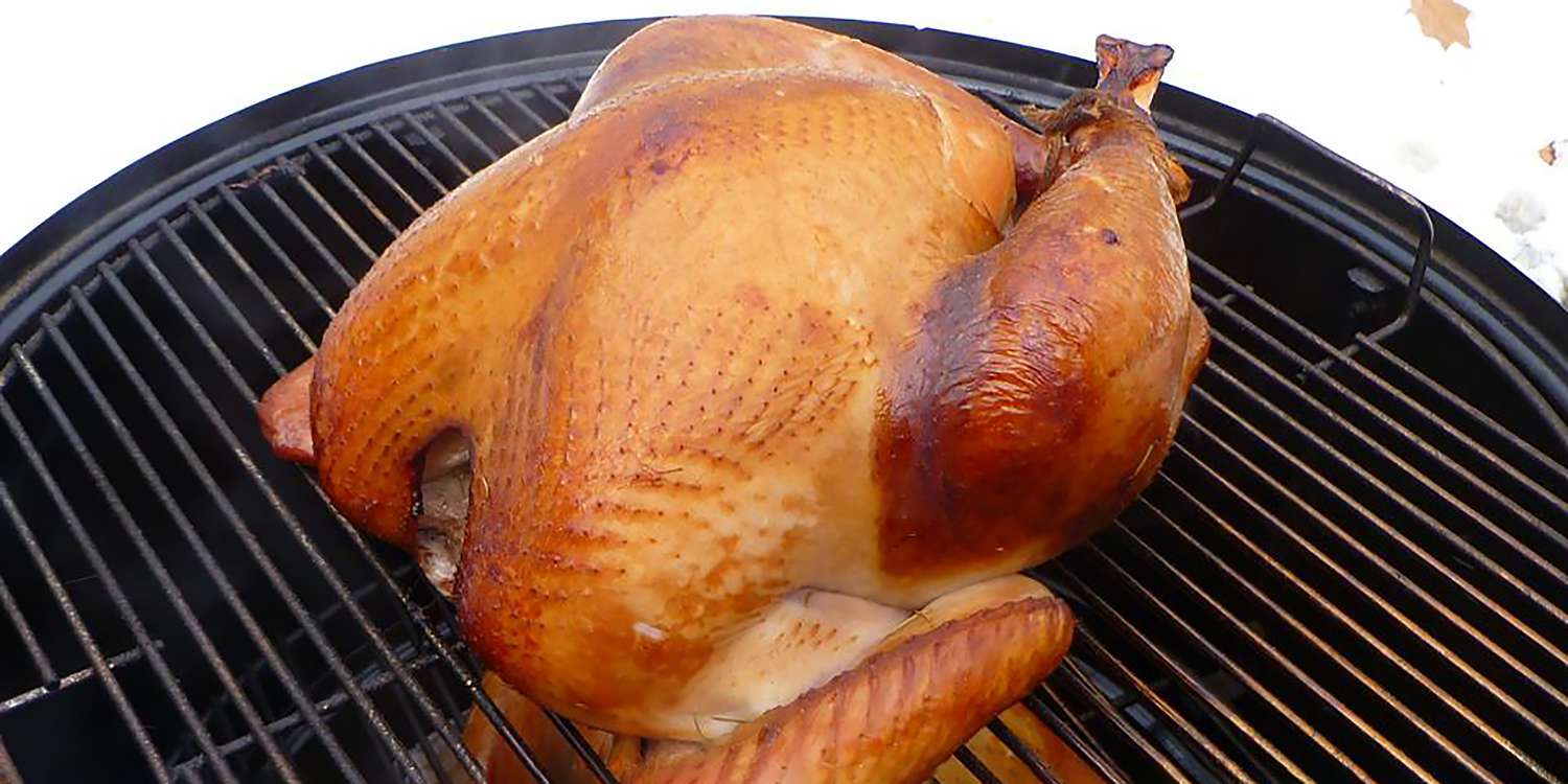 A whole smoked turkey sitting on the grates of a smoker