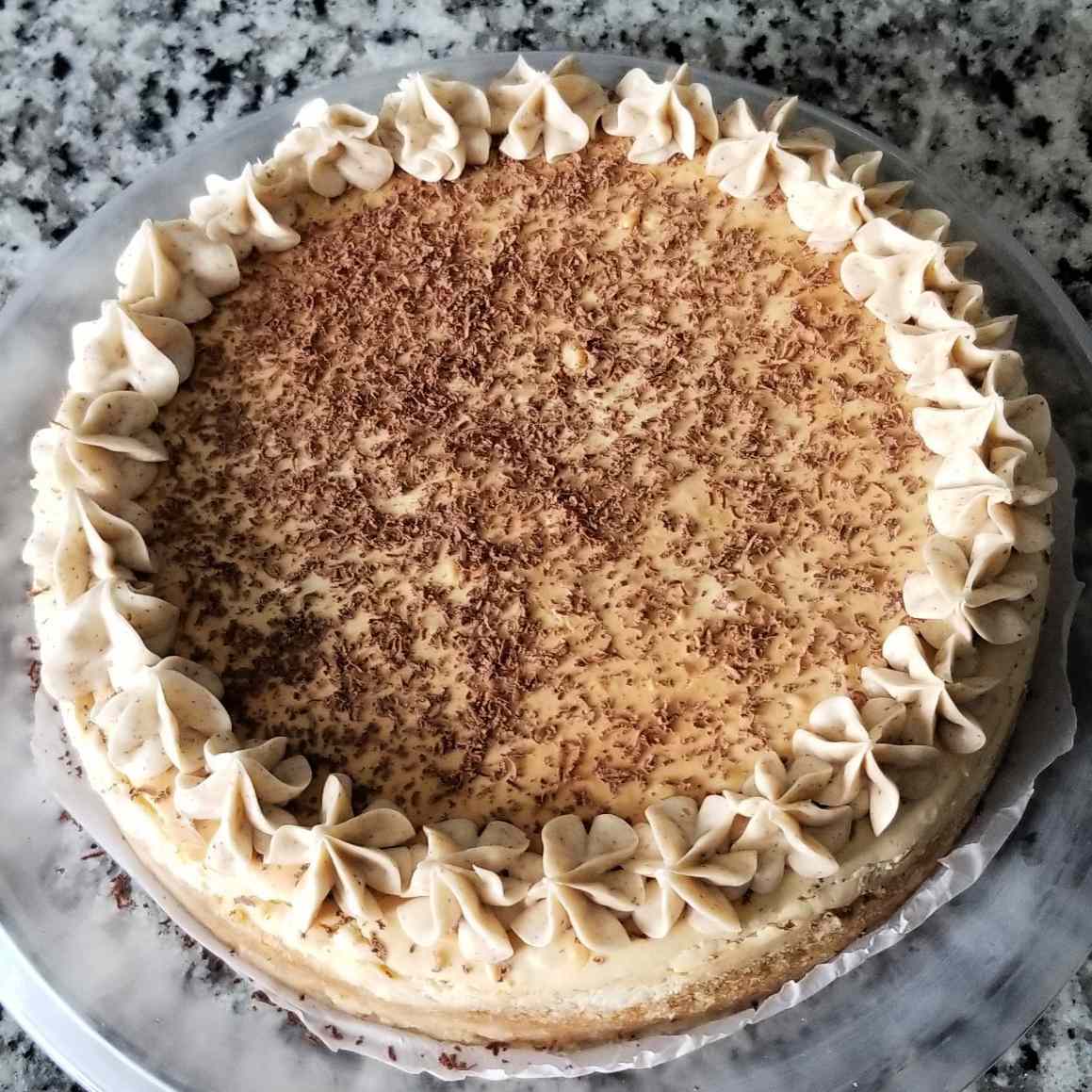 overhead view of Tiramisu Cheesecake recipe decorated with chocolate shavings and frosting rosettes