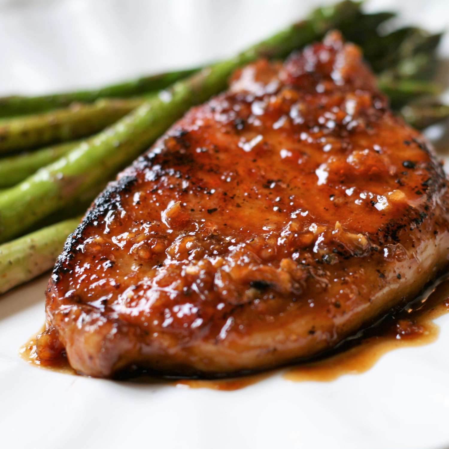 Quick and Easy Honey-Garlic Pork Chops with a side of asparagus on a white plate