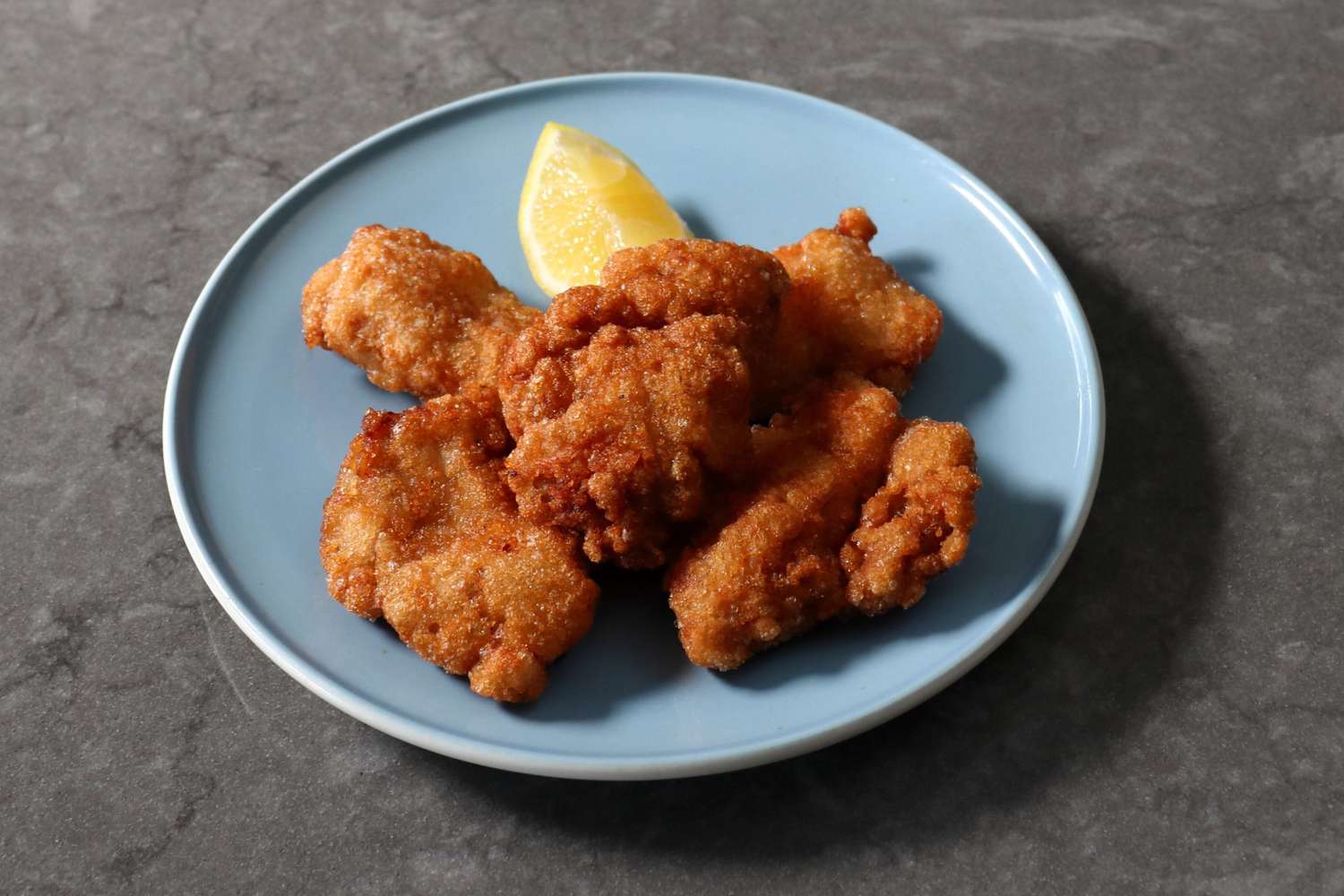 fried chicken pieces with a lemon wedge on a blue plate