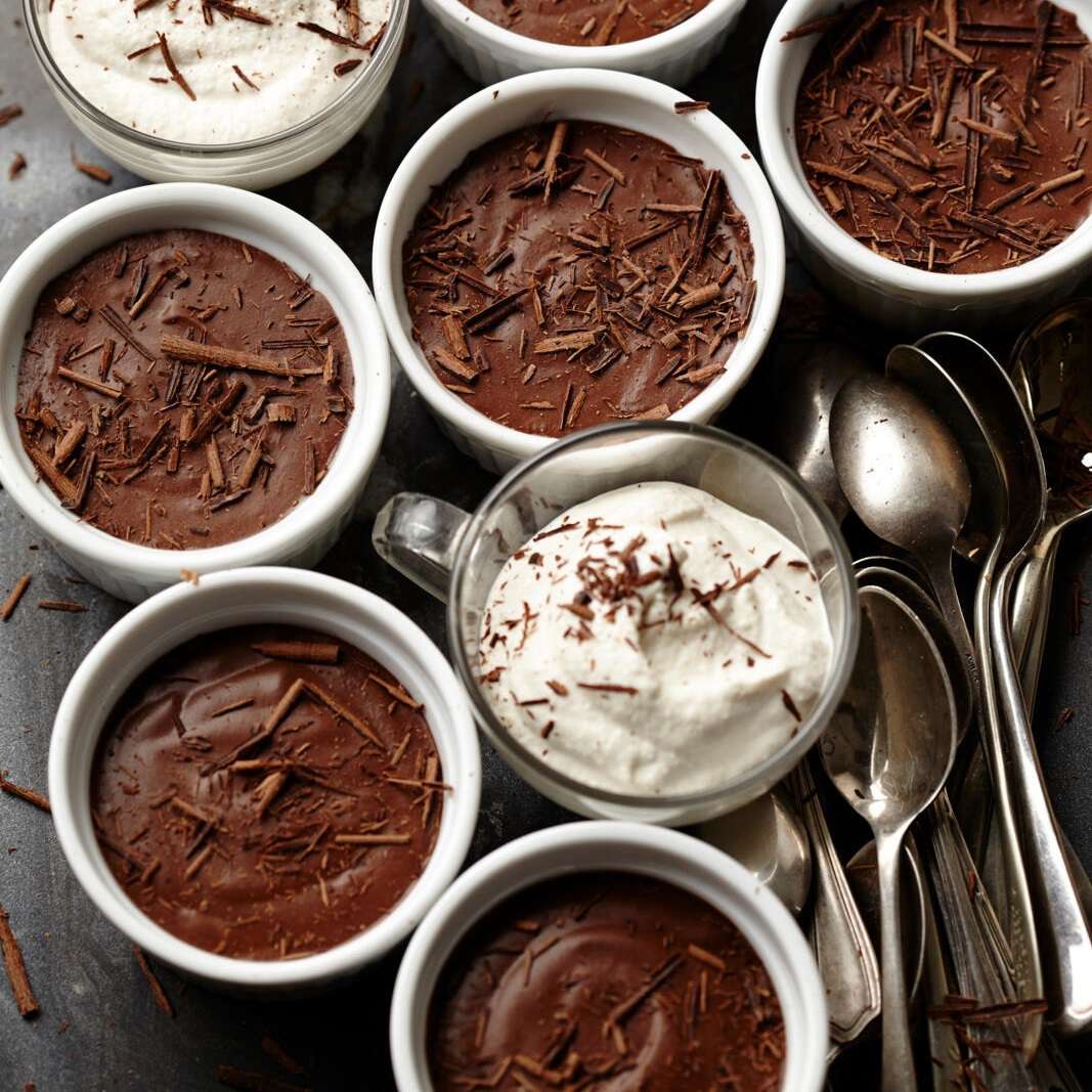 Overhead view of chocolate pots de creme desserts topped with whipped cream and shaved chocolate