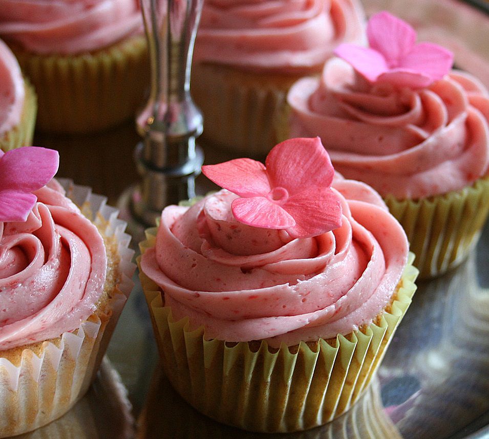 closeup of cupcakes on a display with piped pink frosting garnished with pink flowers