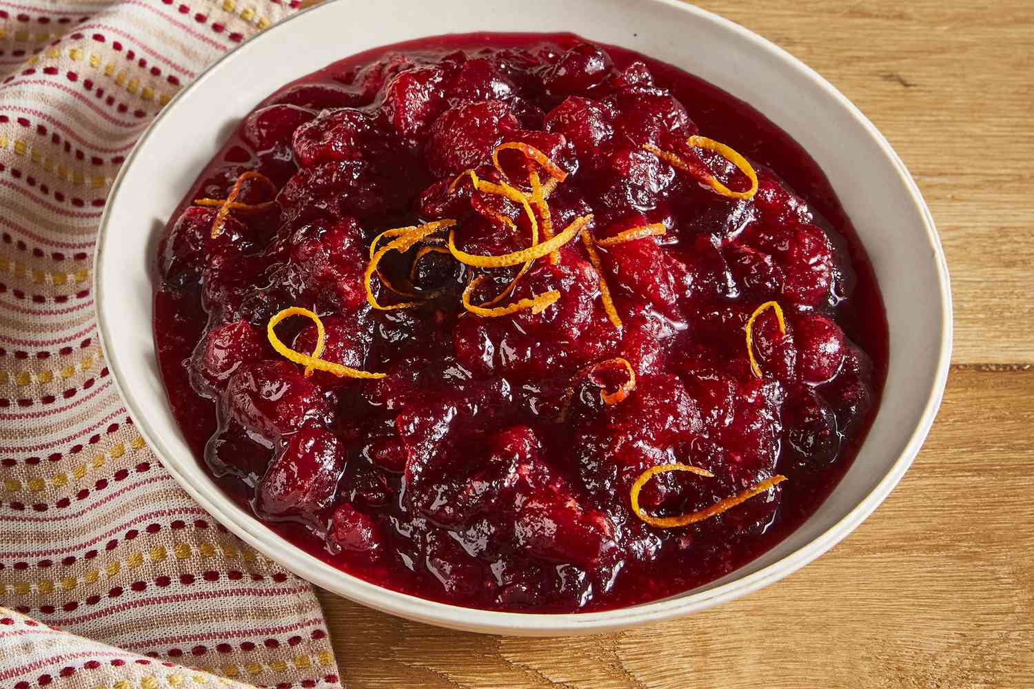 a close up view of a bowl of cranberry sauce topped with fresh orange garnish