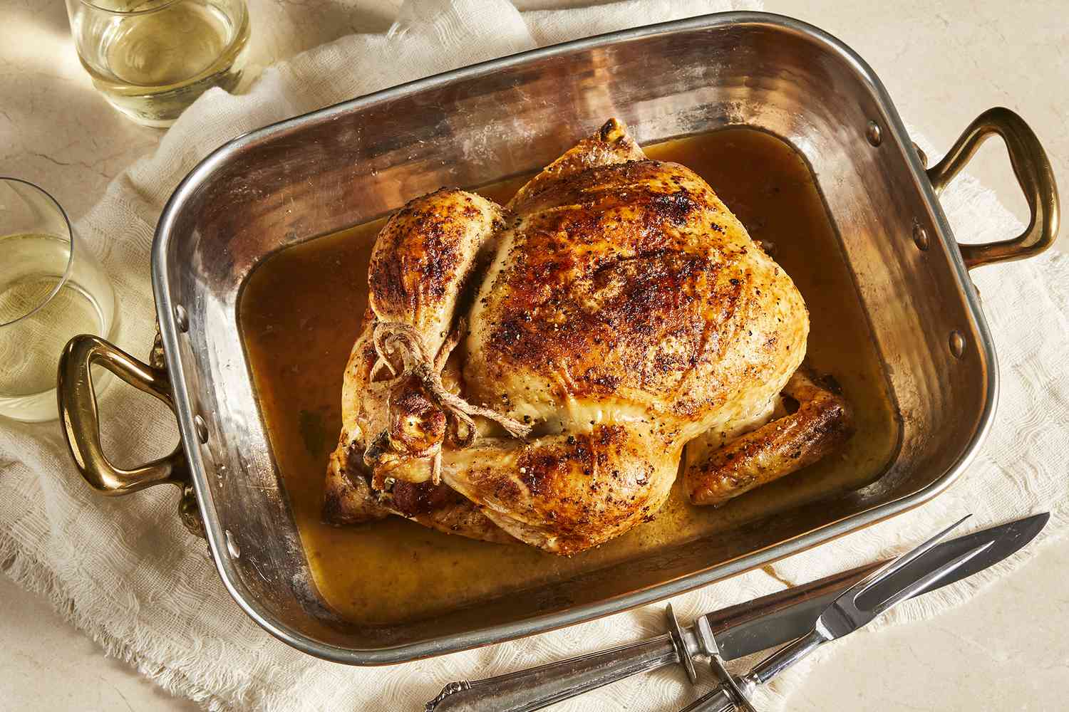 an overhead view of a whole beautiful roasted chicken in a roasting pan.