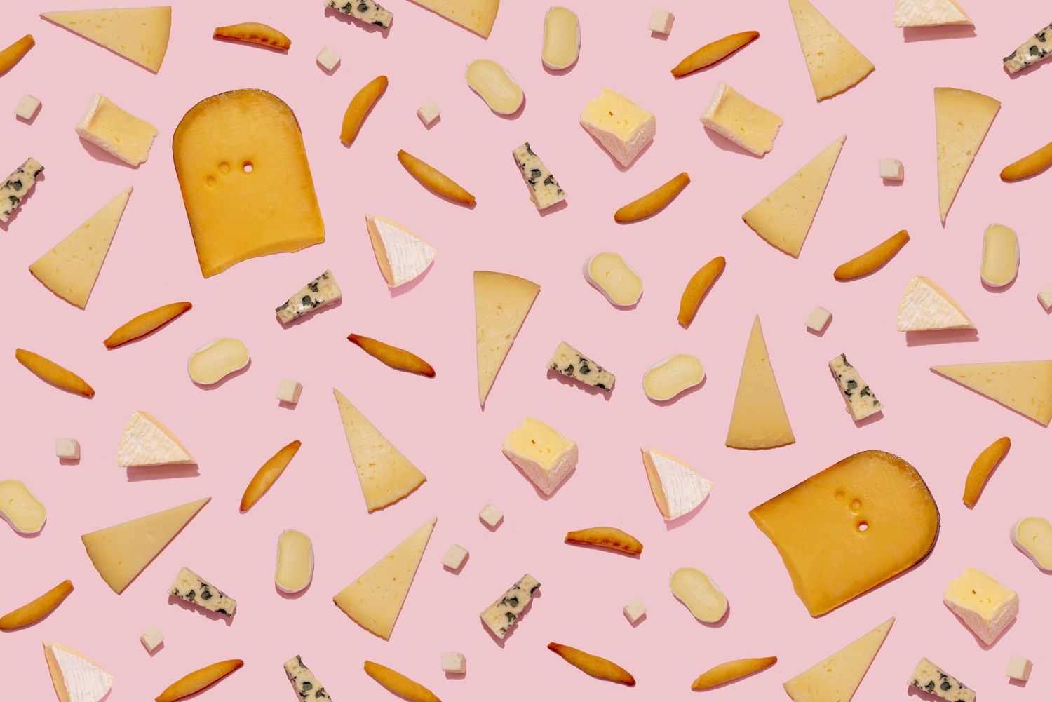 Varieties of cheese and bread sticks on pink background