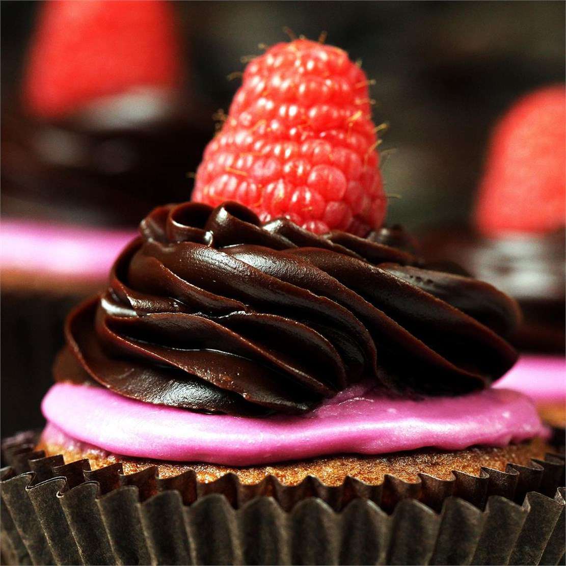 chocolate ganache icing piped on top of a cupcake with raspberry garnish