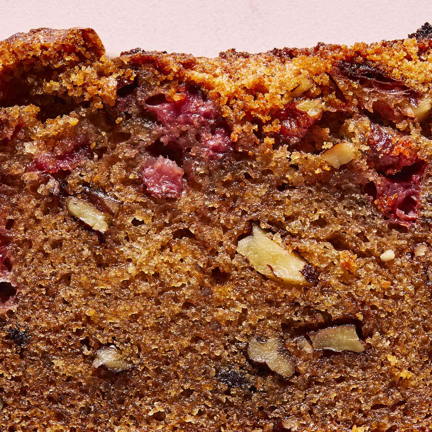 a close up, overhead view of a single slice of strawberry bread with fresh strawberries laying close by