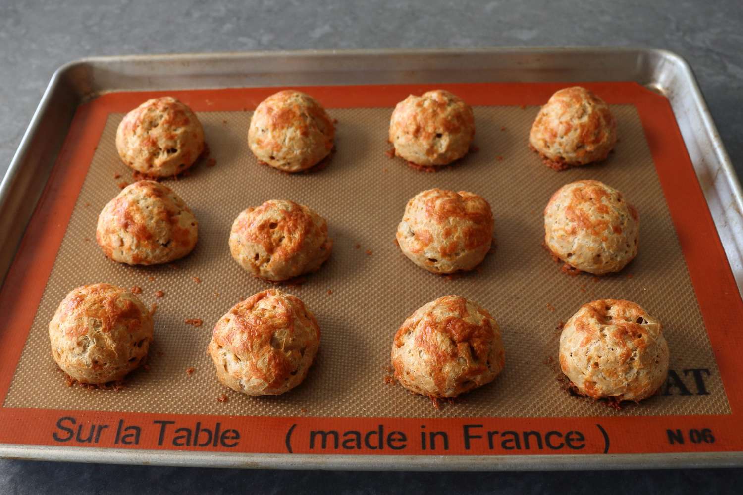 Cheese puffs on a silicone-lined baking sheet