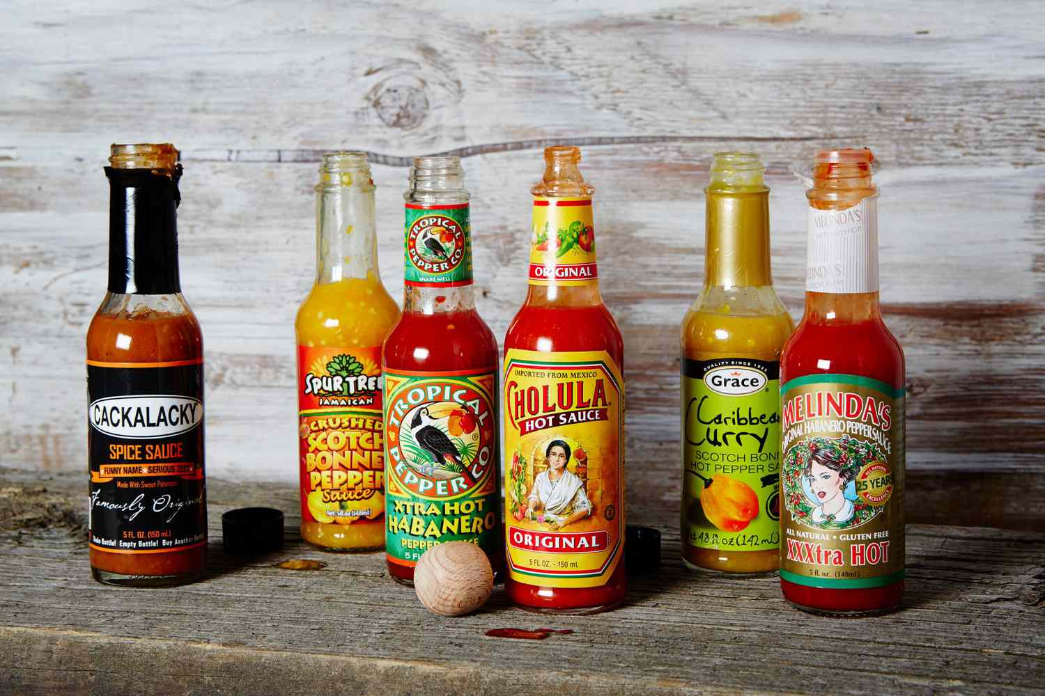 different brands of hot sauce on wooden surface
