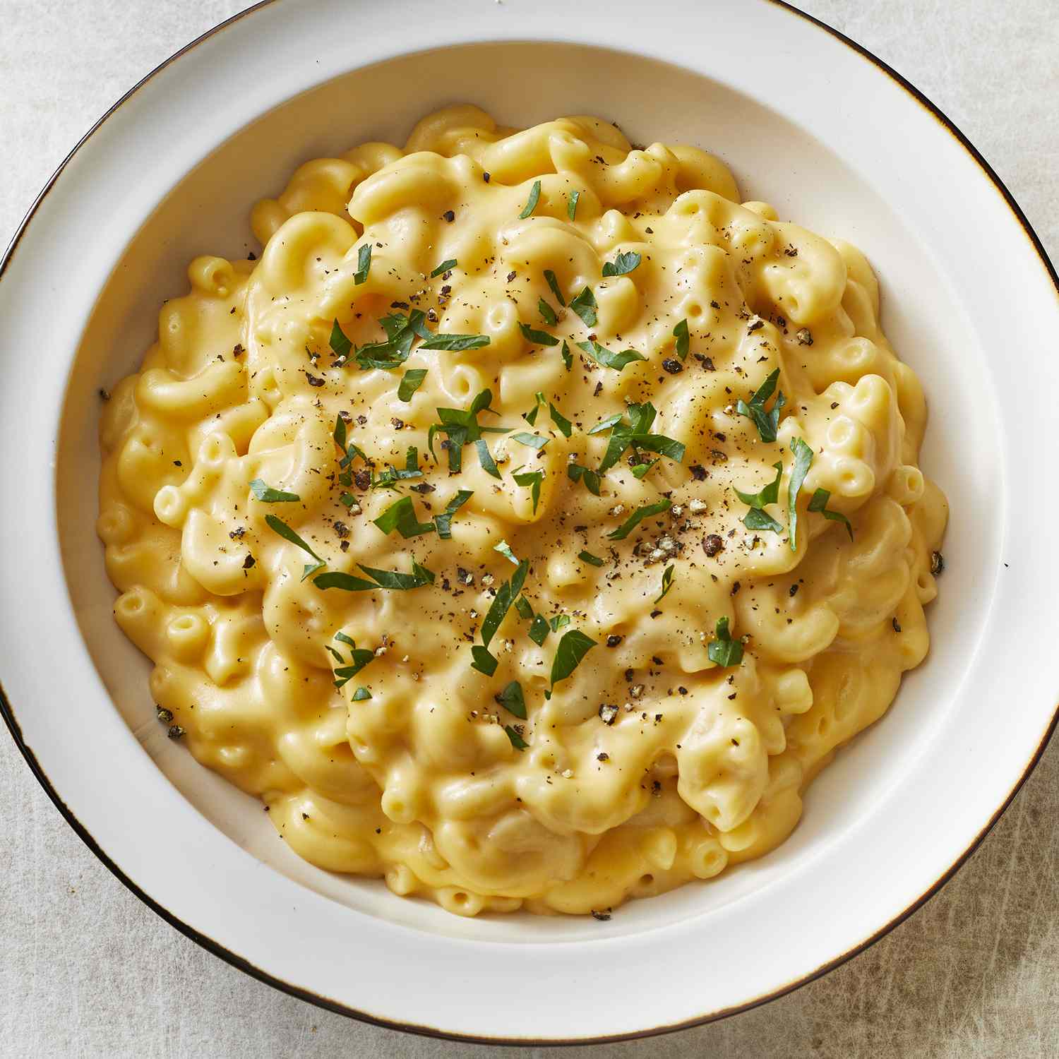 overhead view of a full bowl of creamy macaroni and cheese topped with black pepper and