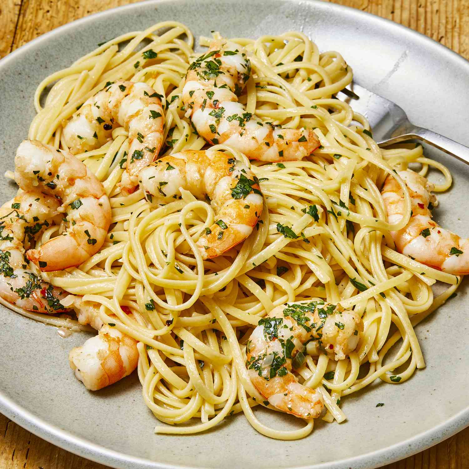 a low angle view of a single serving of shrimp scampi with pasta garnished with fresh chopped parsley