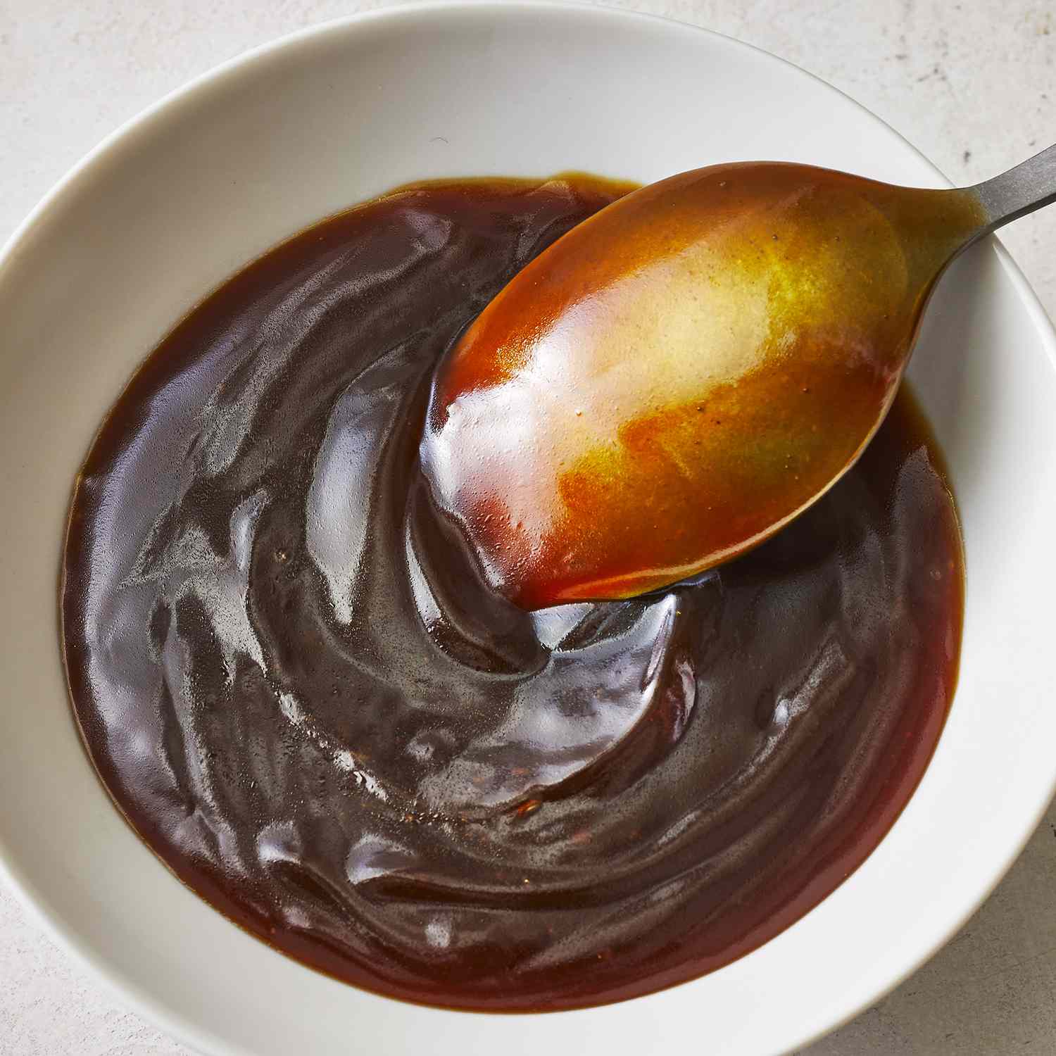 a super close up view of simple teriyaki sauce being stirred with a spoon.