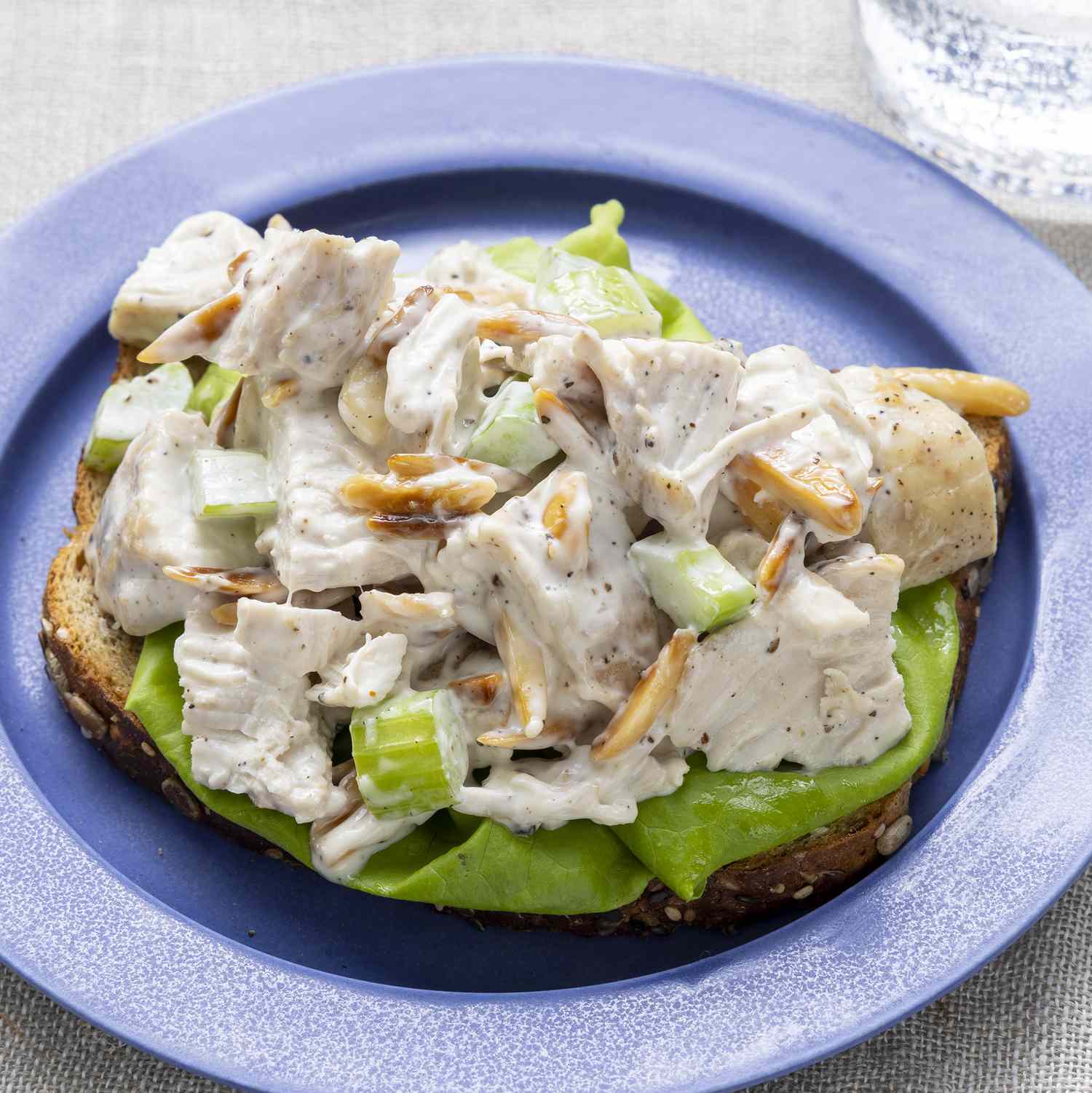 a close up view of basic chicken salad served open faced on a piece of bread with lettuce