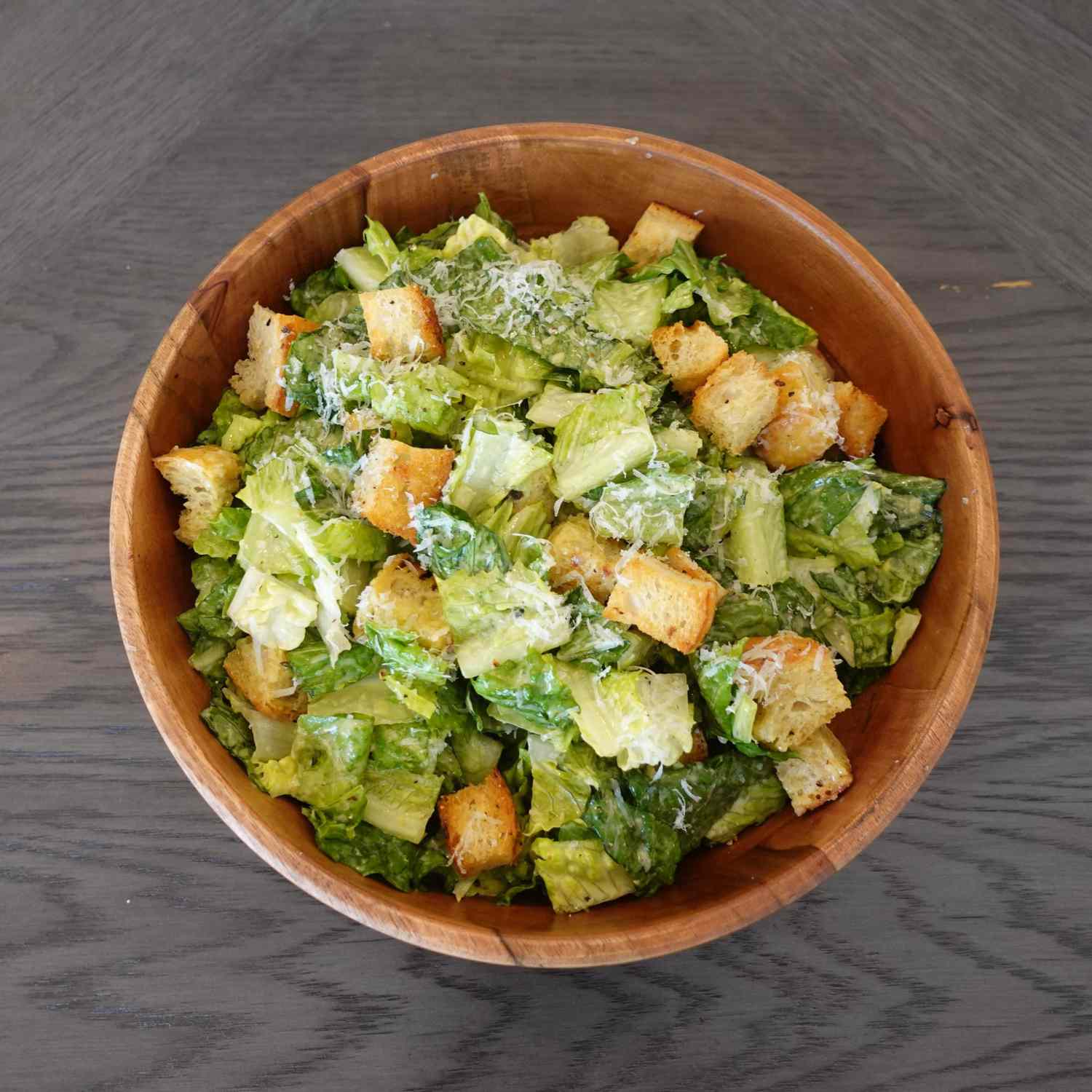Caesar salad with croutons in a wooden salad bowl