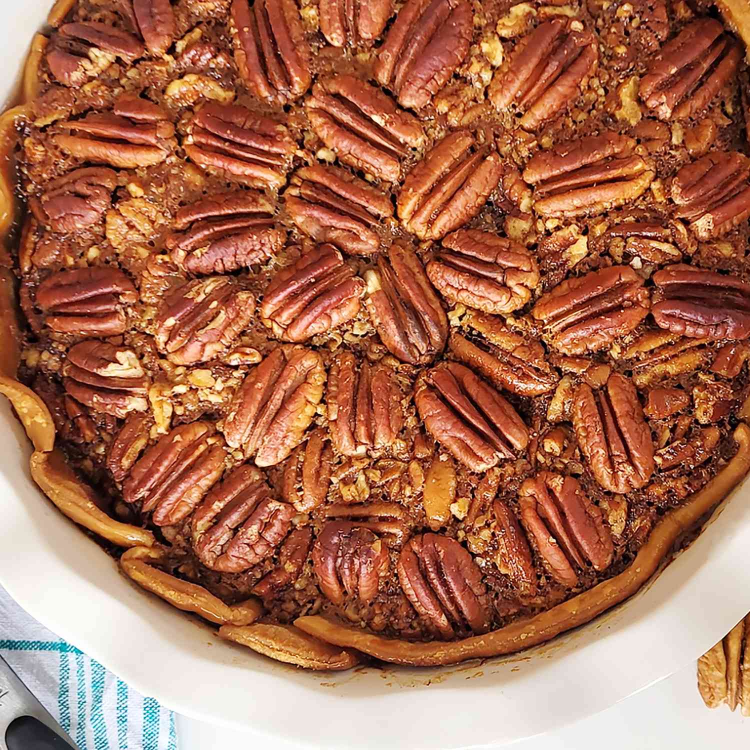 a close up, overhead view of a southern pecan pie in a white pie dish.