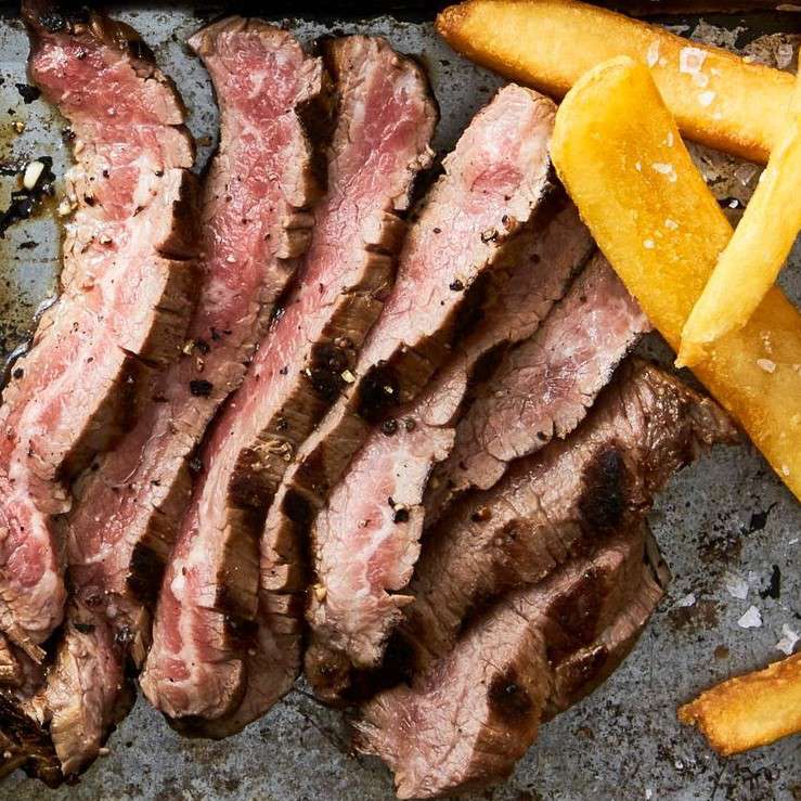 Slices of marinated flank steak with thick-cut French fries