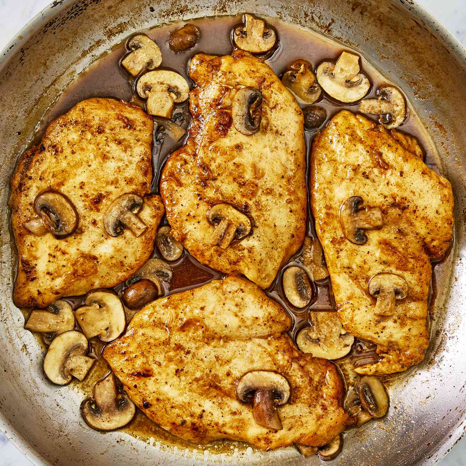 an overhead, close-up view of chicken marsala in a skillet.