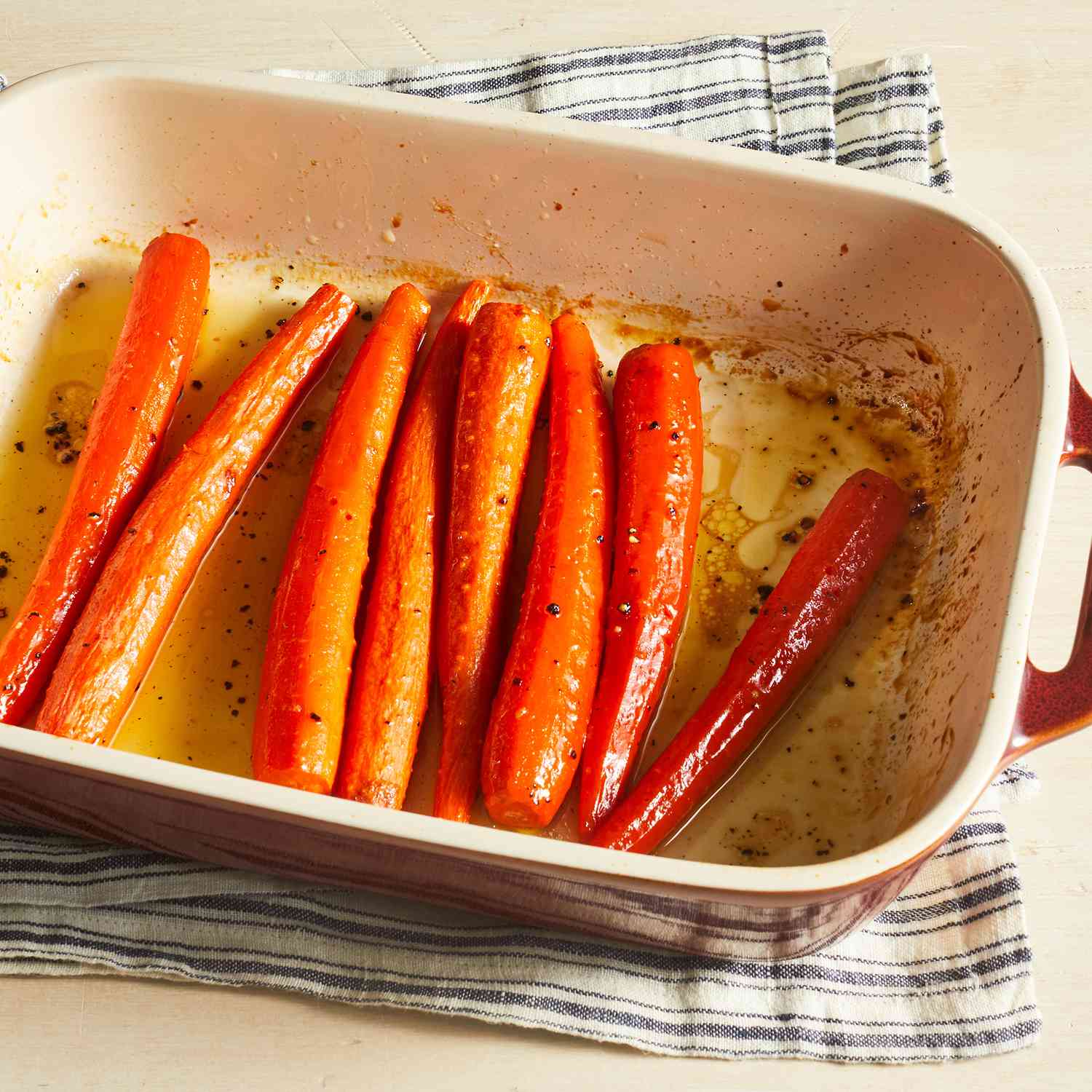 a high angle, close up view of honey roasted carrots in a white rectangular baking dish.