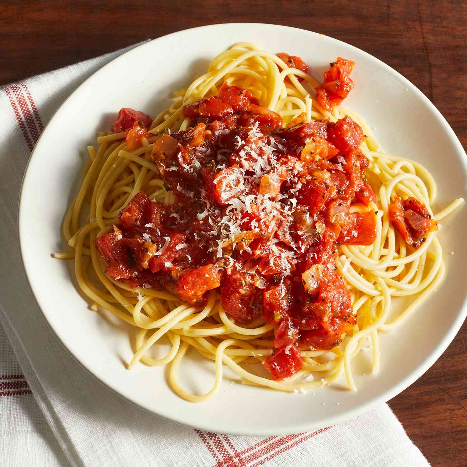 a single plate of spaghetti with sauce made from fresh tomatoes.