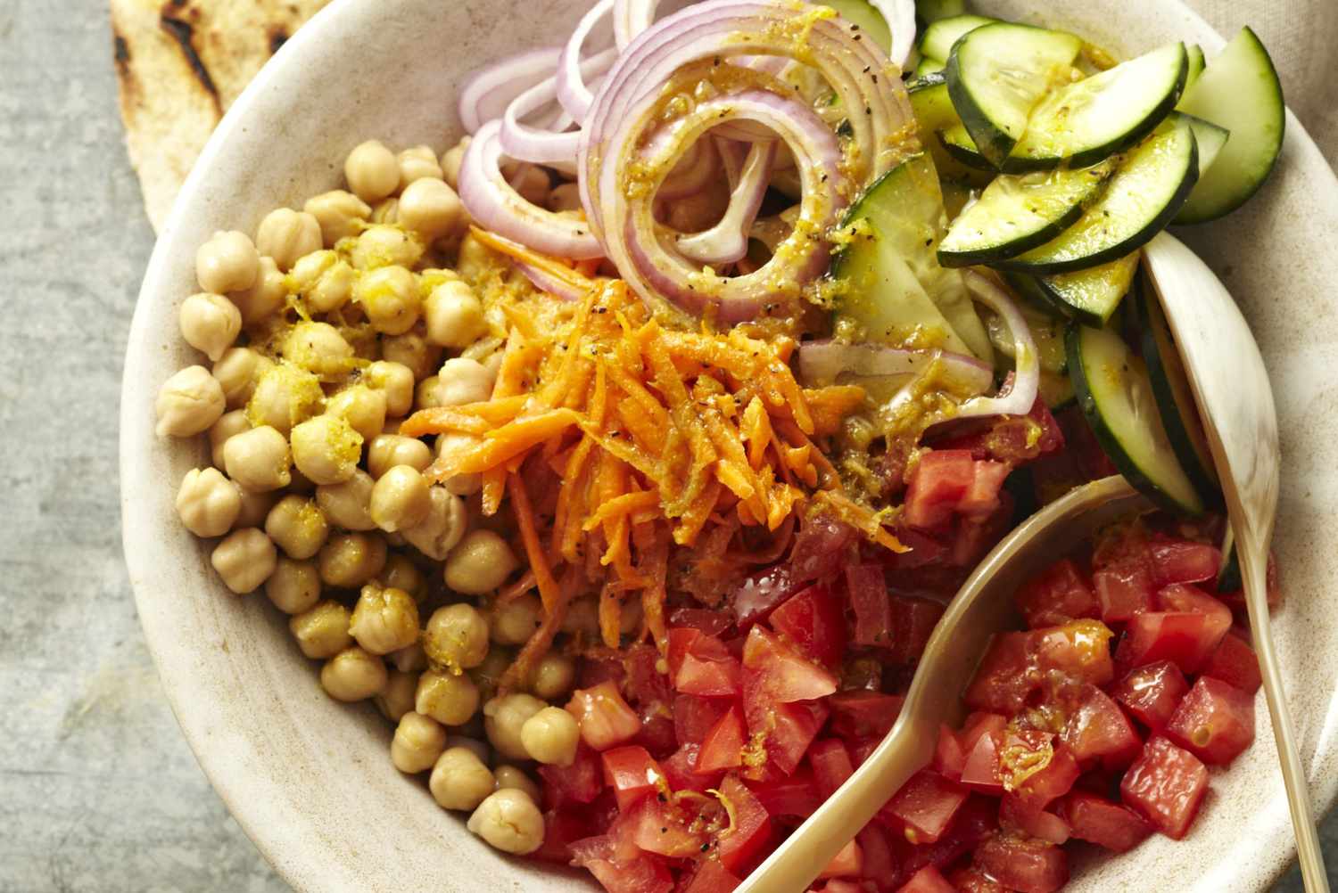 garbanzo bean salad with tomatoes, cucumber, shredded carrots, purple onions, and pita