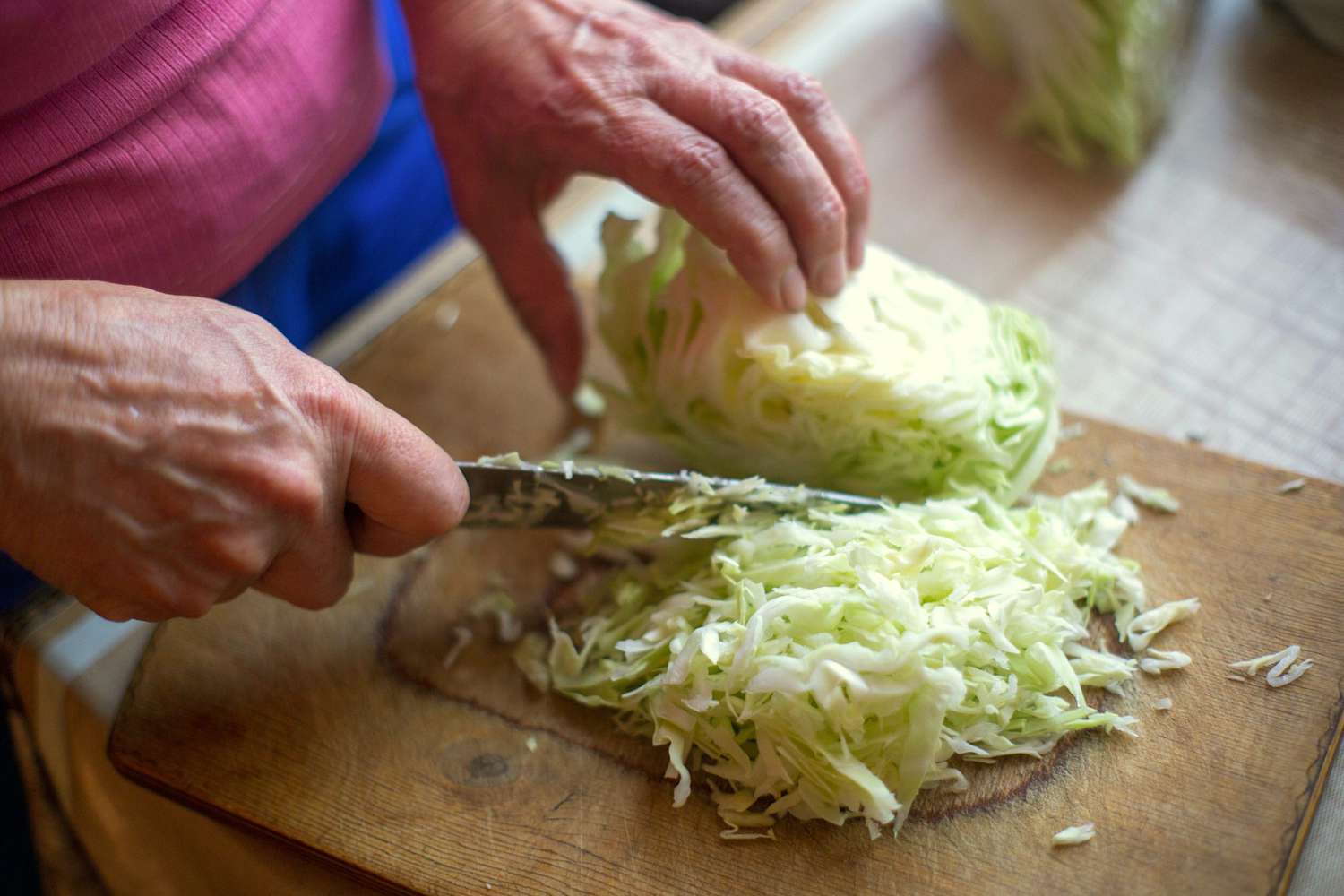 Female hands with a knife chop cabbage for cooking fresh salad