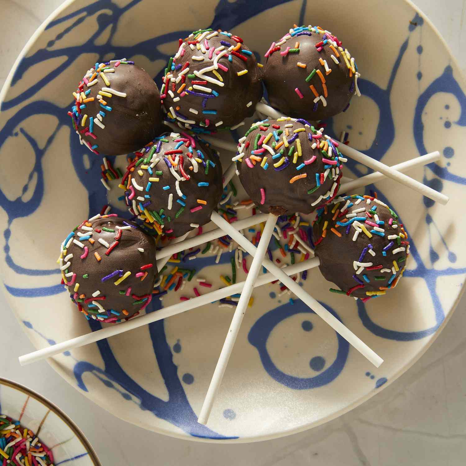 overhead view looking at a plate of chocolate covered cake pops topped with sprinkles