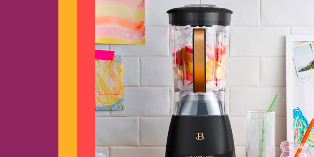 A chic black and gold blender filled with fruit on a kitchen counter