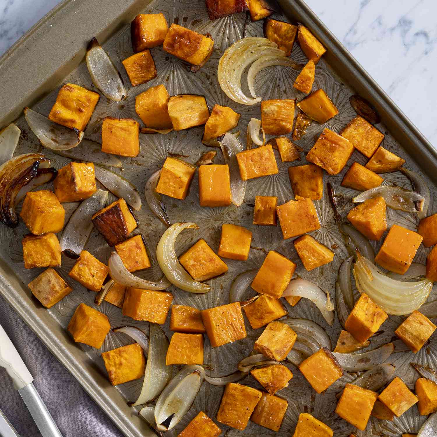 overhead view of oven roasted sweet potatoes on a sheet pan