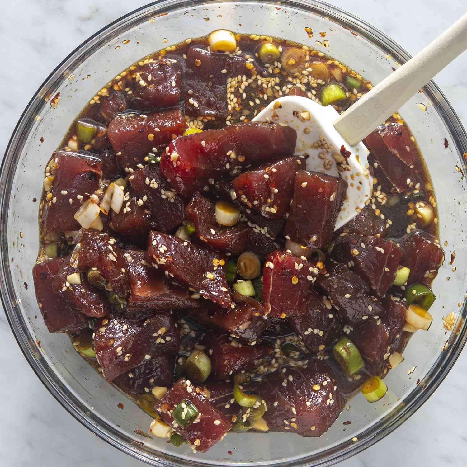 close up view with ahi poke in a glass bowl, with a spatula