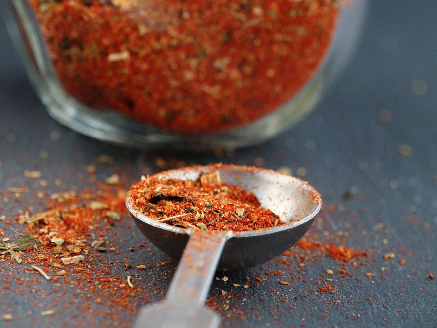 close up view of creole seasoning blend in a spoon and in a jar
