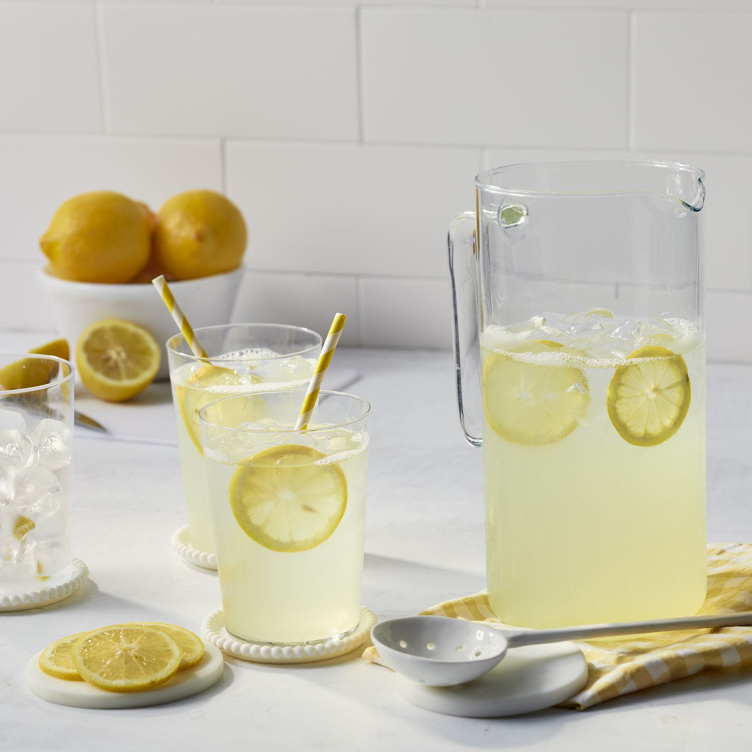 view of lemonade in a pitcher and in glasses, with lemons in a bowl in the background