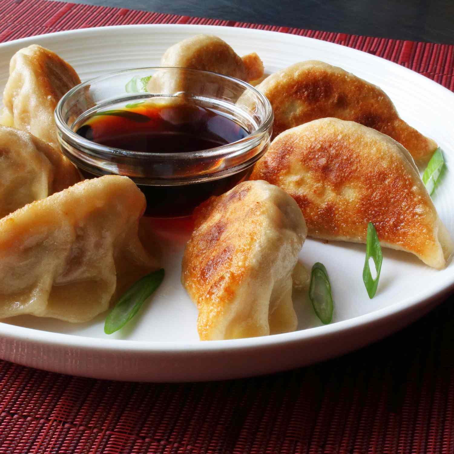 close up view of Pot Stickers on a plate with sauce in a small bowl