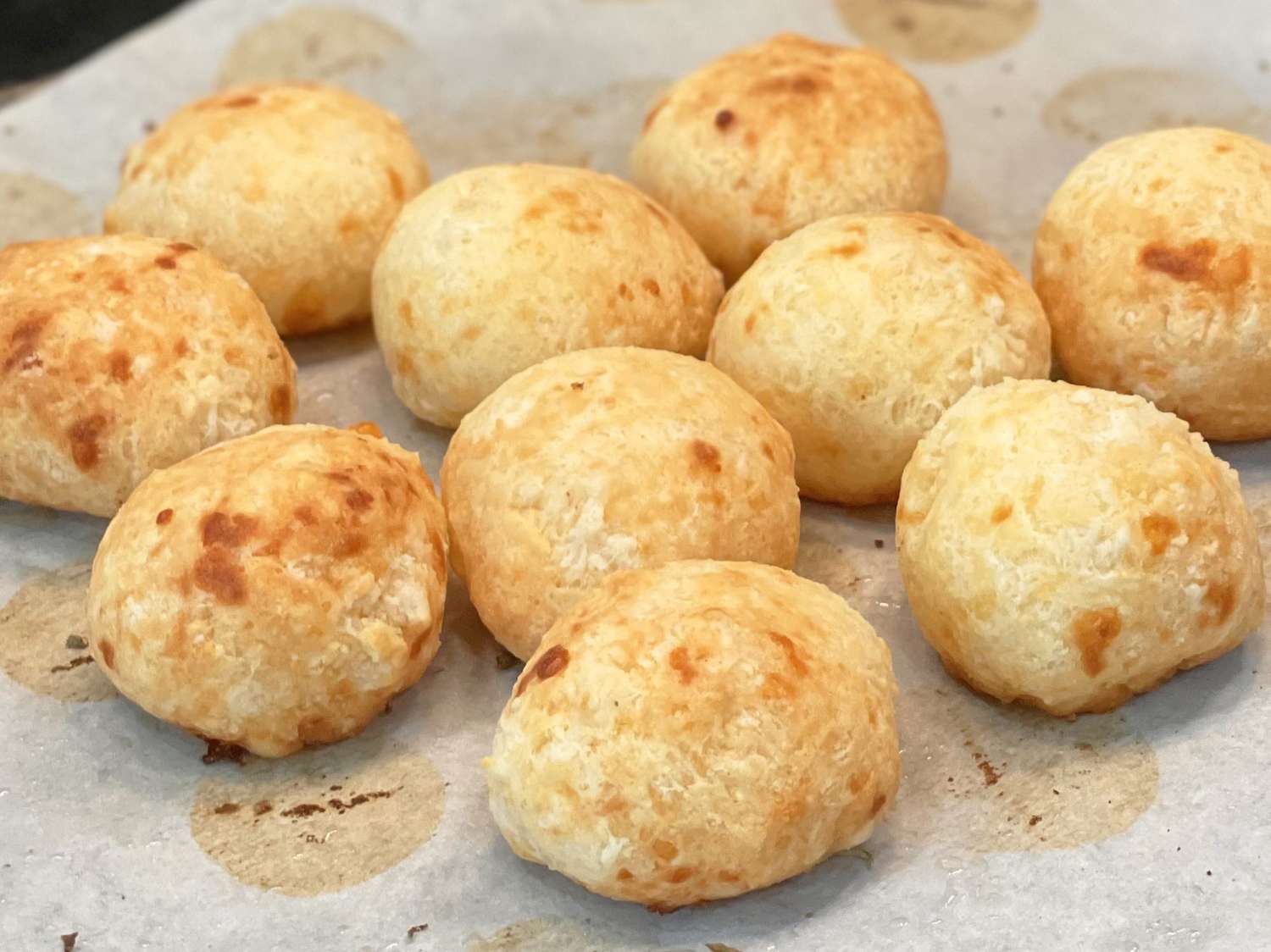 close up view of Brazilian Cheese Bread (Pao de Queijo) on a parchment paper lined baking sheet