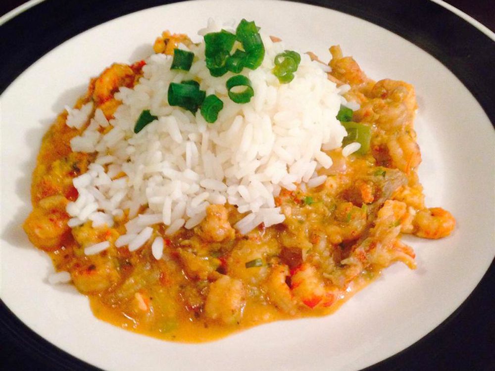 close up view of Louisiana Crawfish Étouffée with rice in a bowl, with green onions on top