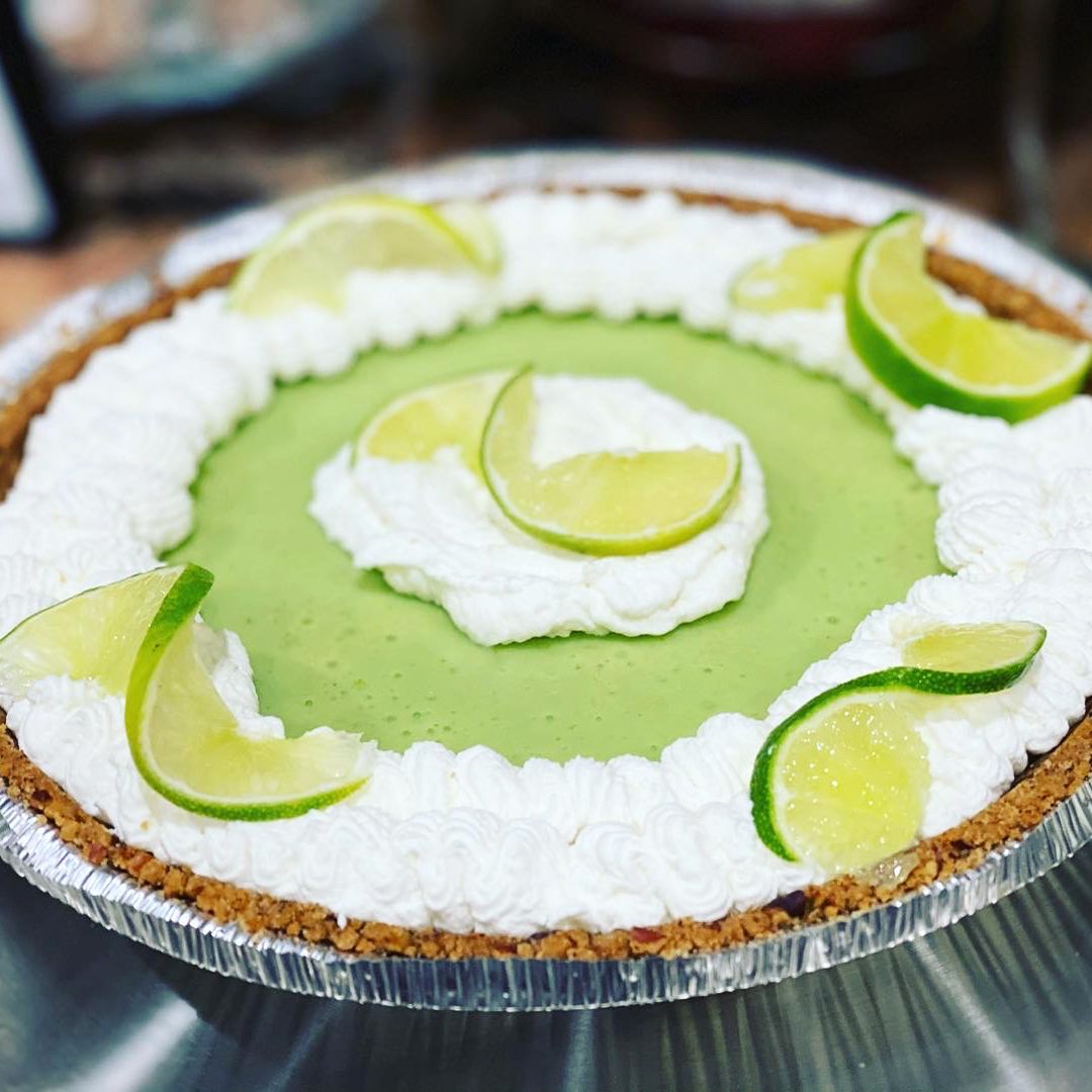 close up view of a Key Lime Pie garnished with cream and lime slices