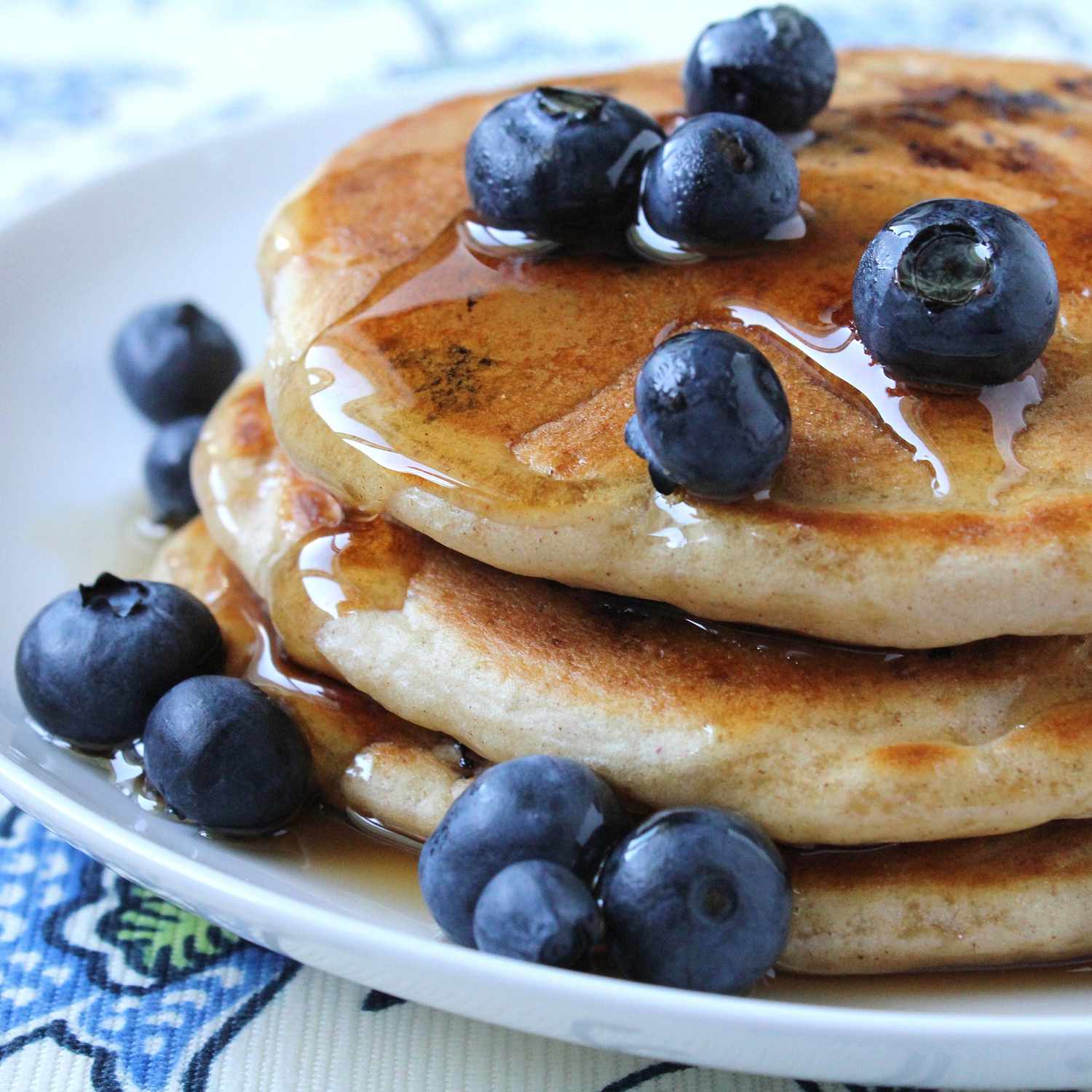 close up view of Todd's Famous Blueberry Pancakes on a plate, garnished with blueberries and syrup