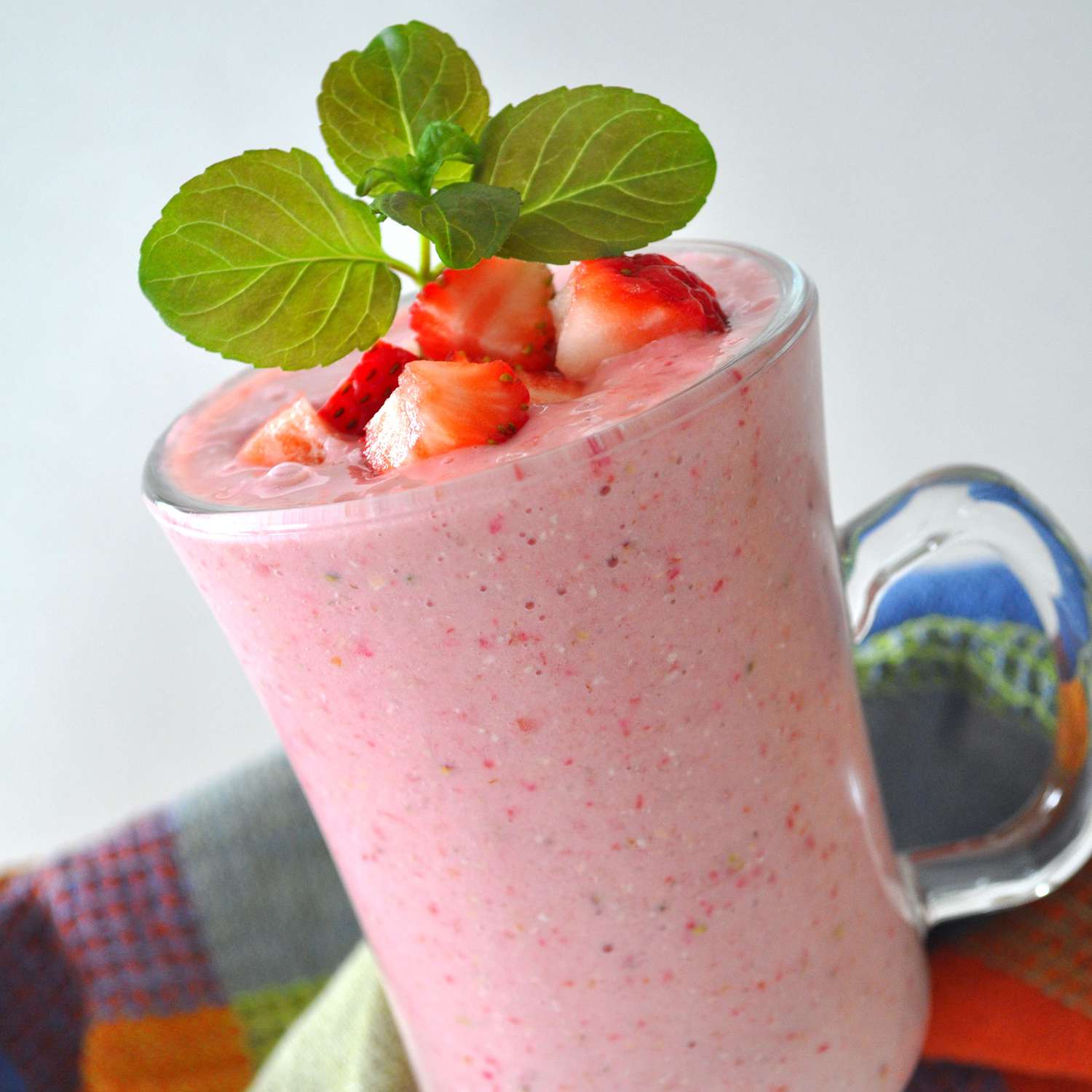 close up view of Strawberry Oatmeal Breakfast Smoothie in a glass, garnished with strawberries and mint