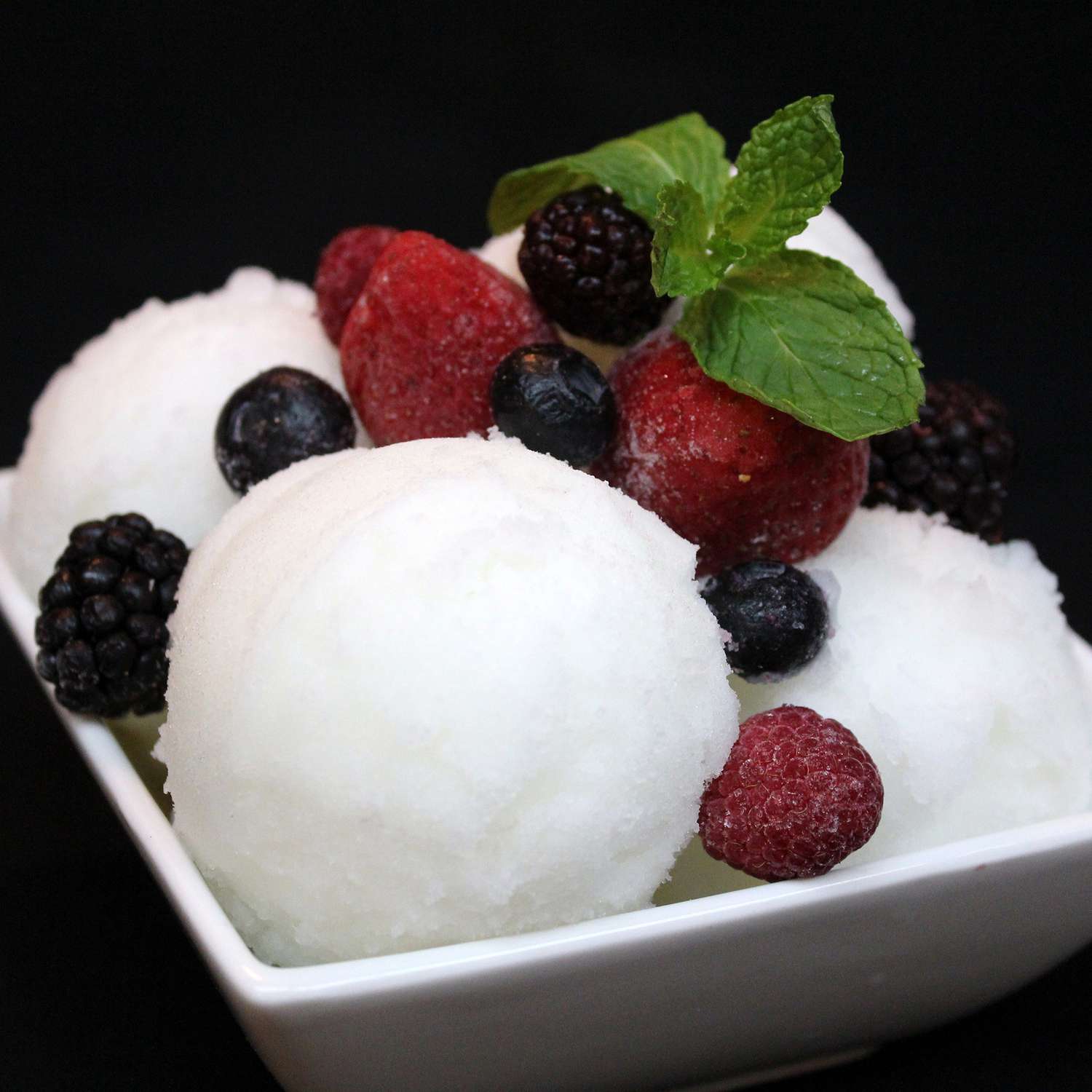 close up view of Snow Ice Cream with berries and mint on top in a bowl
