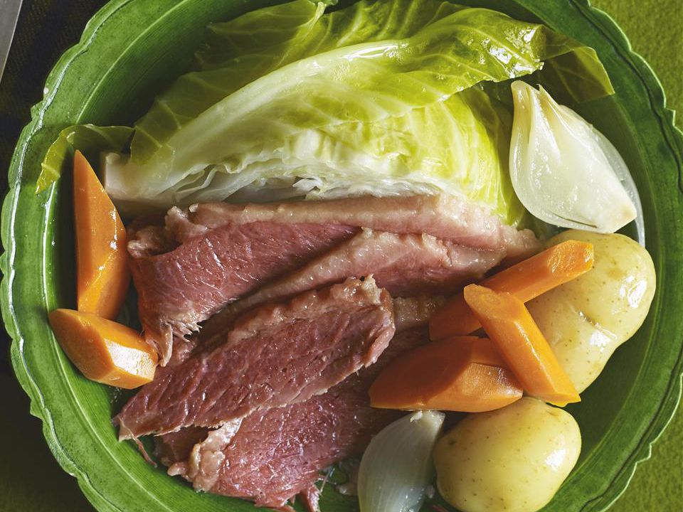 close up view of Corned Beef on a green plate with cabbage, potatoes, and carrots