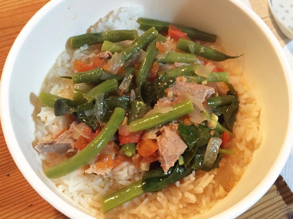 overhead view of Pork Sinigang over rice in a white bowl